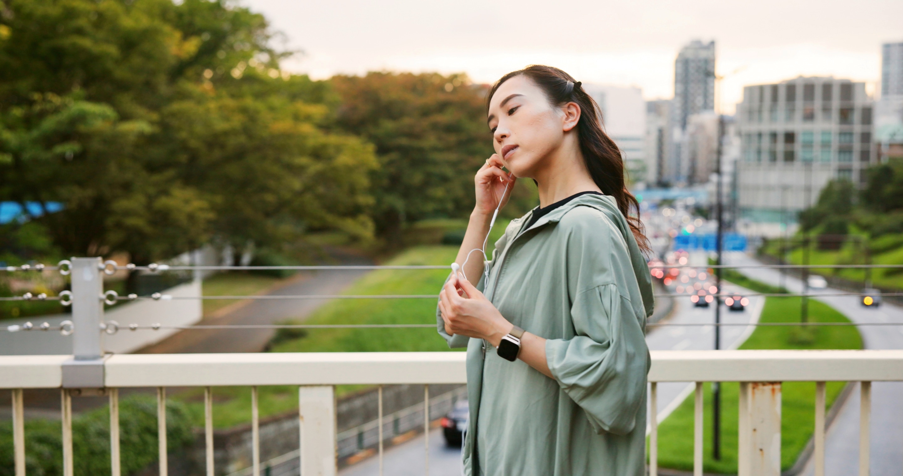Woman on a walk putting on earphones.