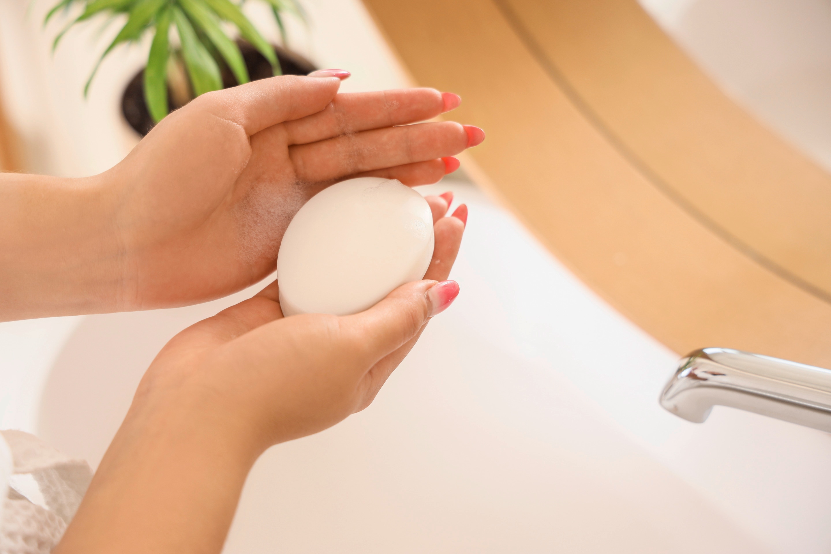 ada sabun mandi batangan yang digenggam di atas wastafel kamar mandi.