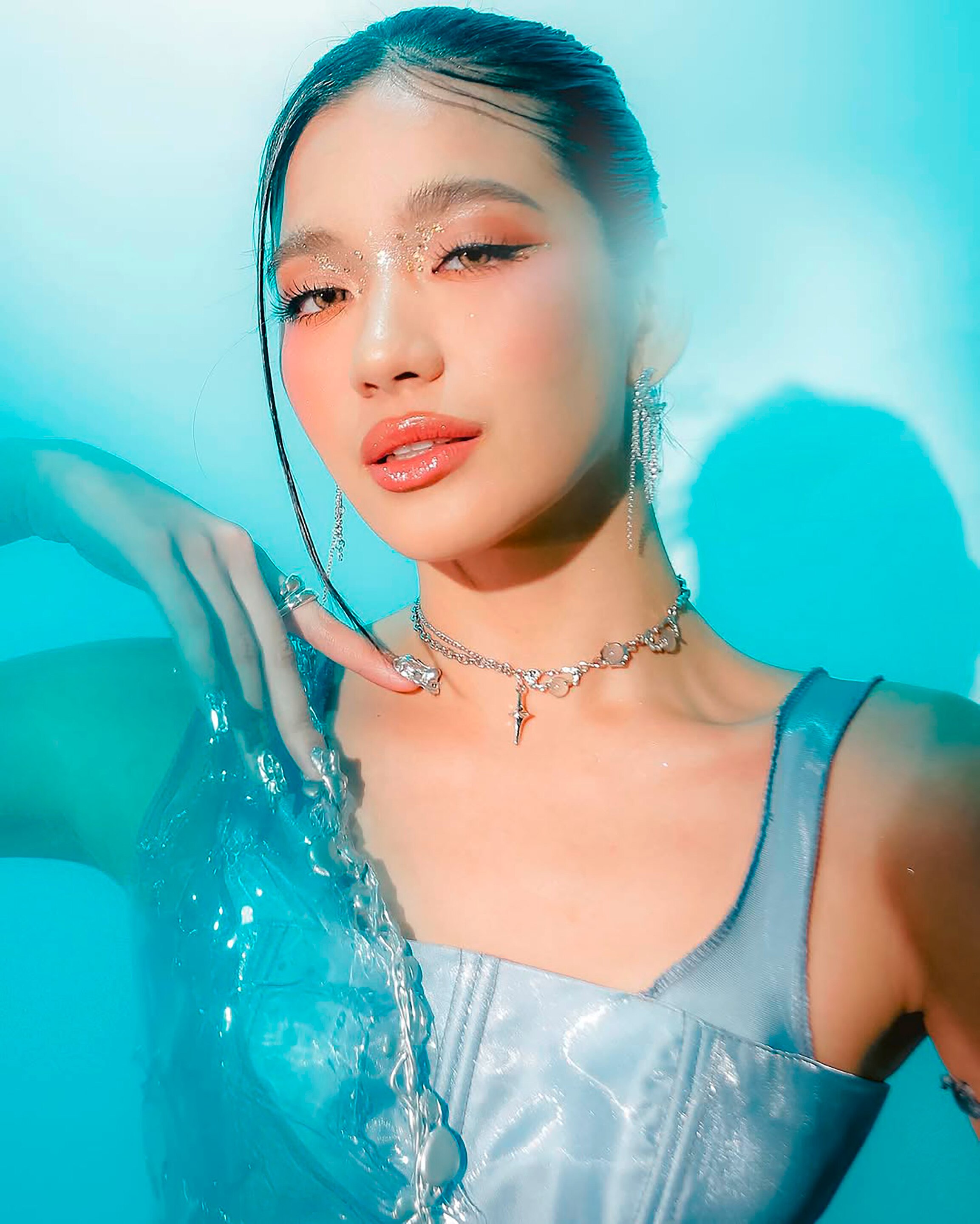 Woman with face crystals and glam makeup smiling softly.