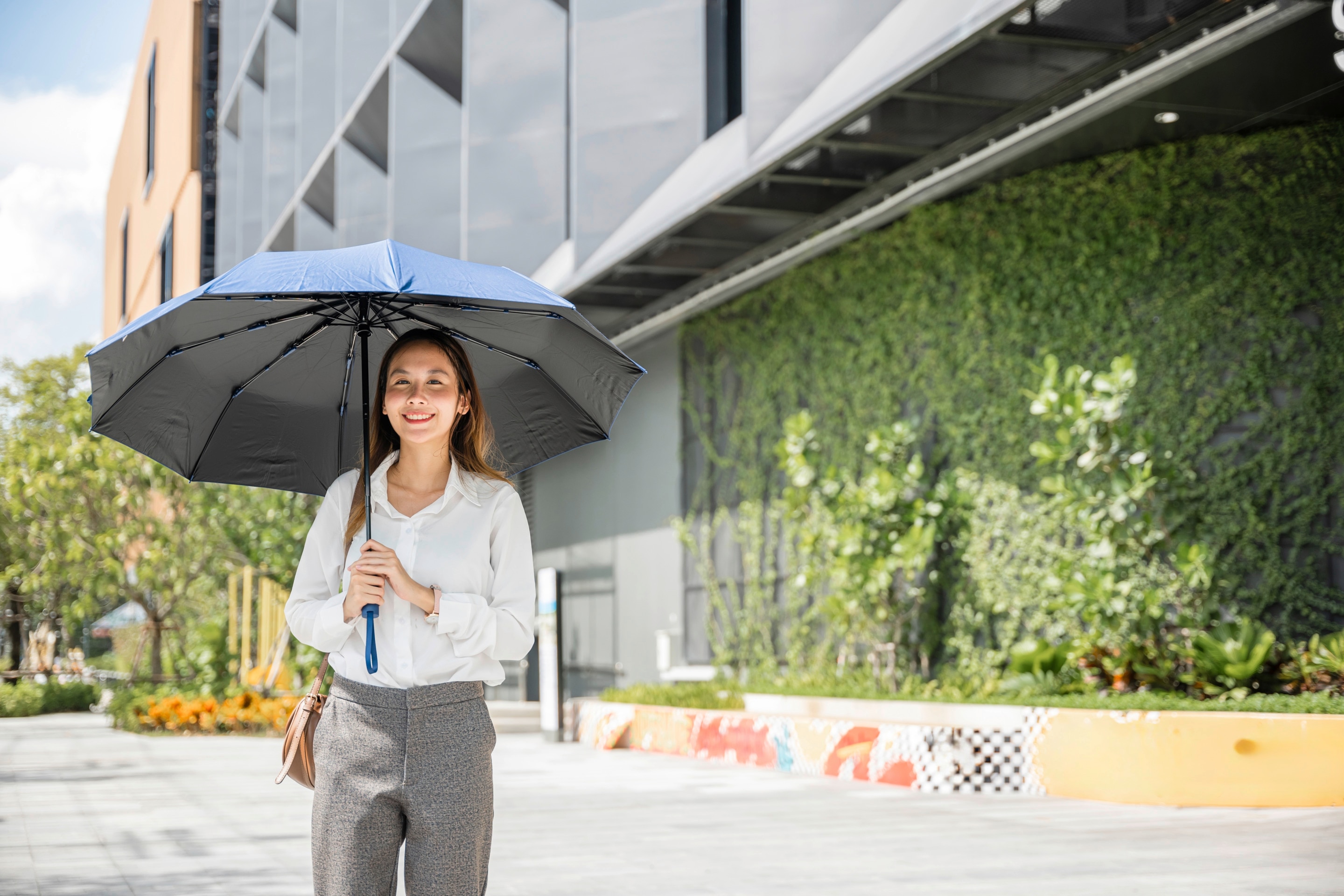 Asian woman outdoors holding an umbrella.