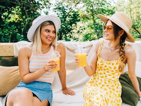 Two women enjoying Orange Creamsicle® cocktails outdoors in summer