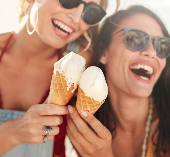 Two women enjoying Breyers® Natural Vanilla Ice Cream in sugar cones