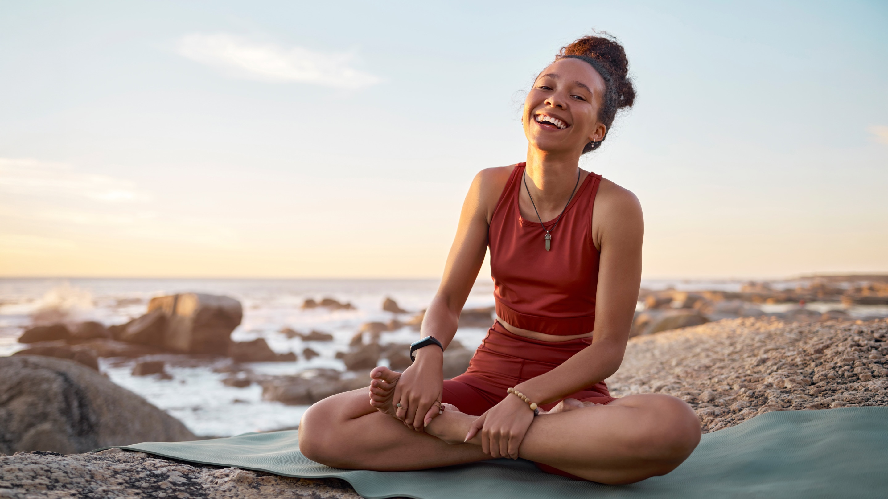 Young African American woman doing yoga on the beach with no sign of acne caused by sweat
