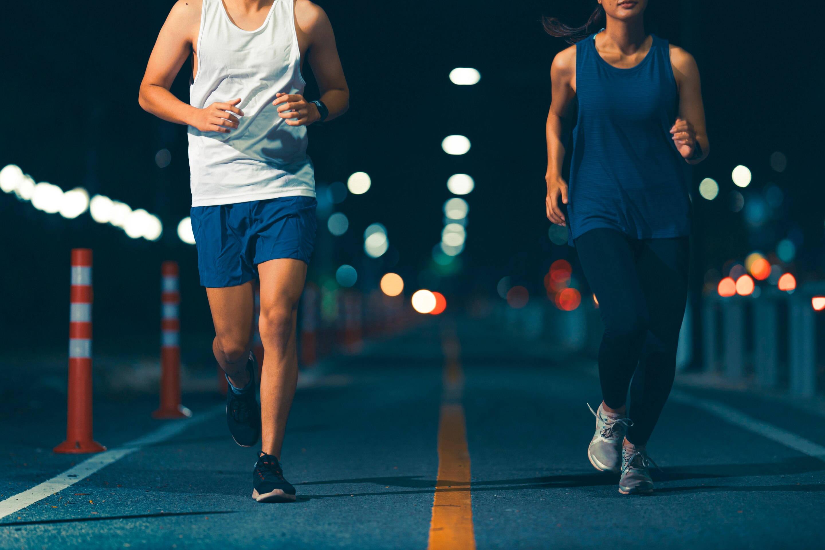 ada dua orang berlari di jalan kota pada malam hari sebagai contoh aktivitas olahraga malam.