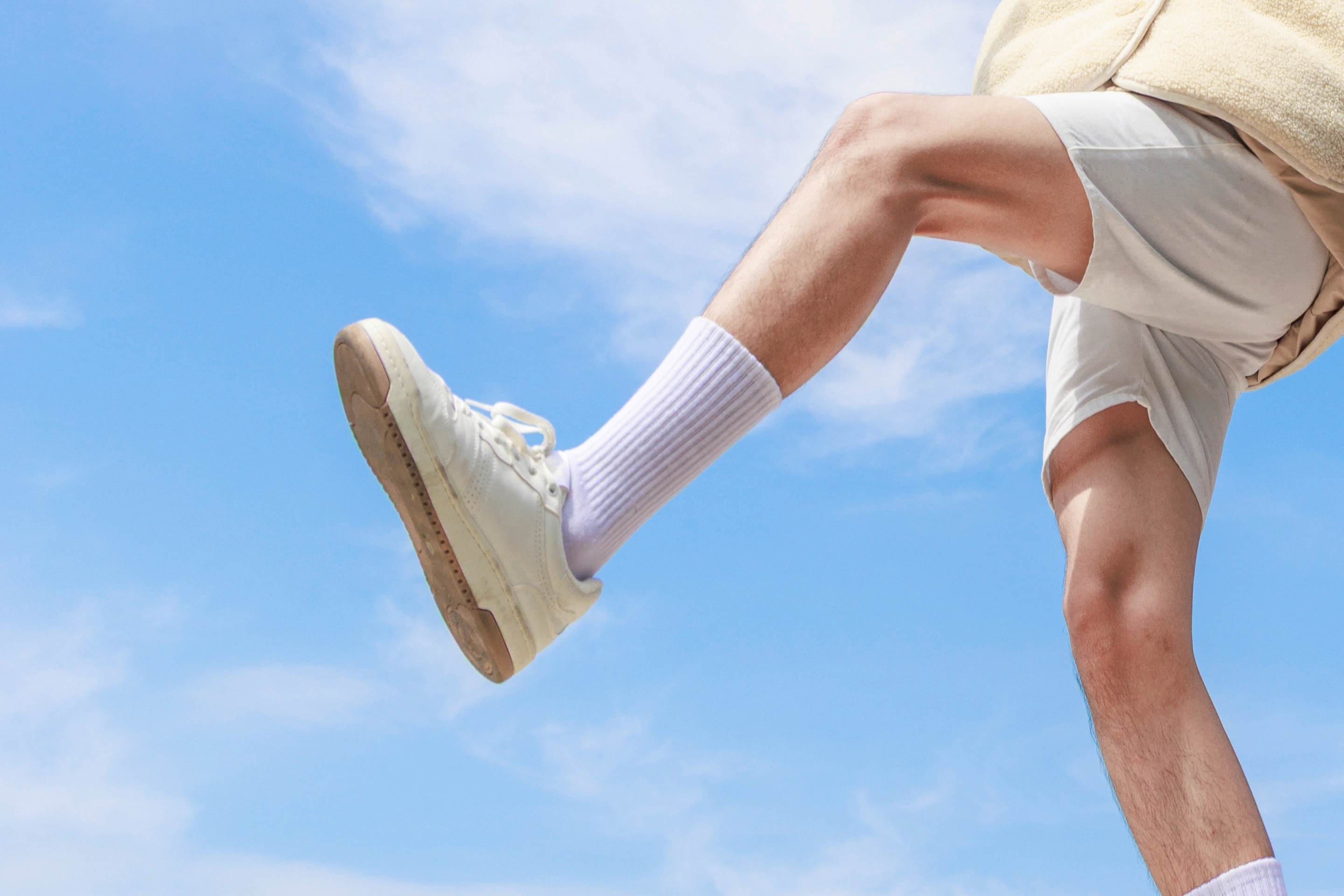 ada kaki seseorang memakai sepatu dan kaus kaki di luar ruangan yang menggambarkan penyebab telapak kaki berkeringat.