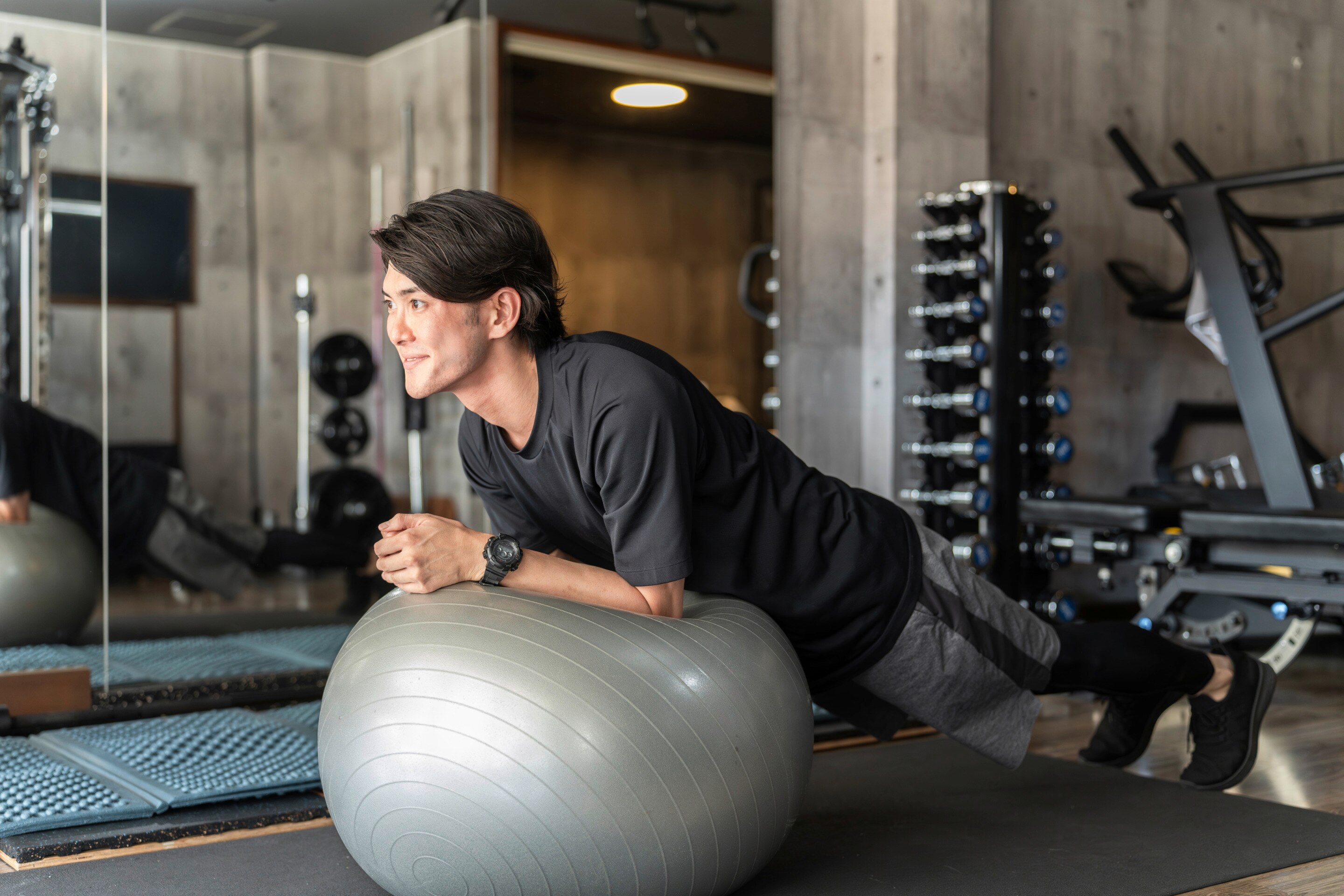 ada seorang pria Asia sedang melakukan olahraga plank dengan bola