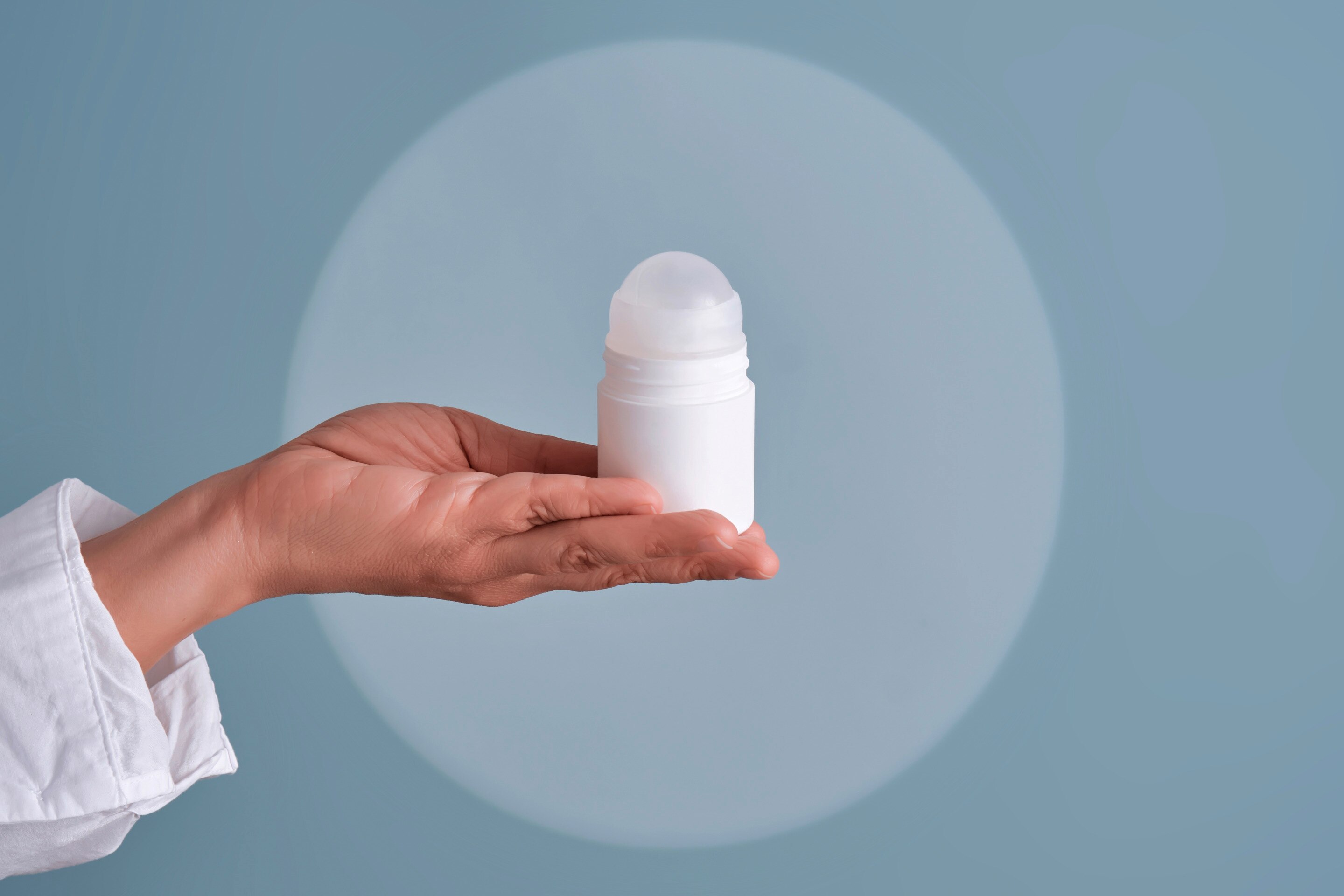 botol deodorant berwarna putih sedang digenggam.