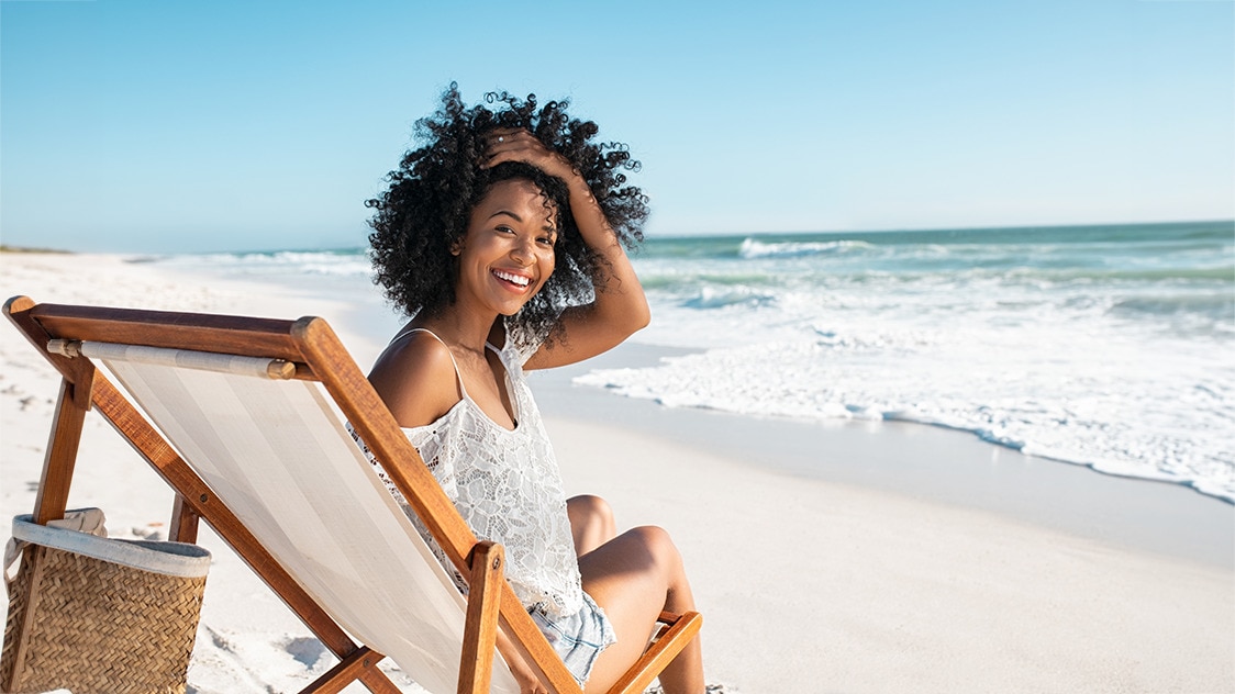 Young African American woman sitting on the beach with melanin hyperpigmentation 