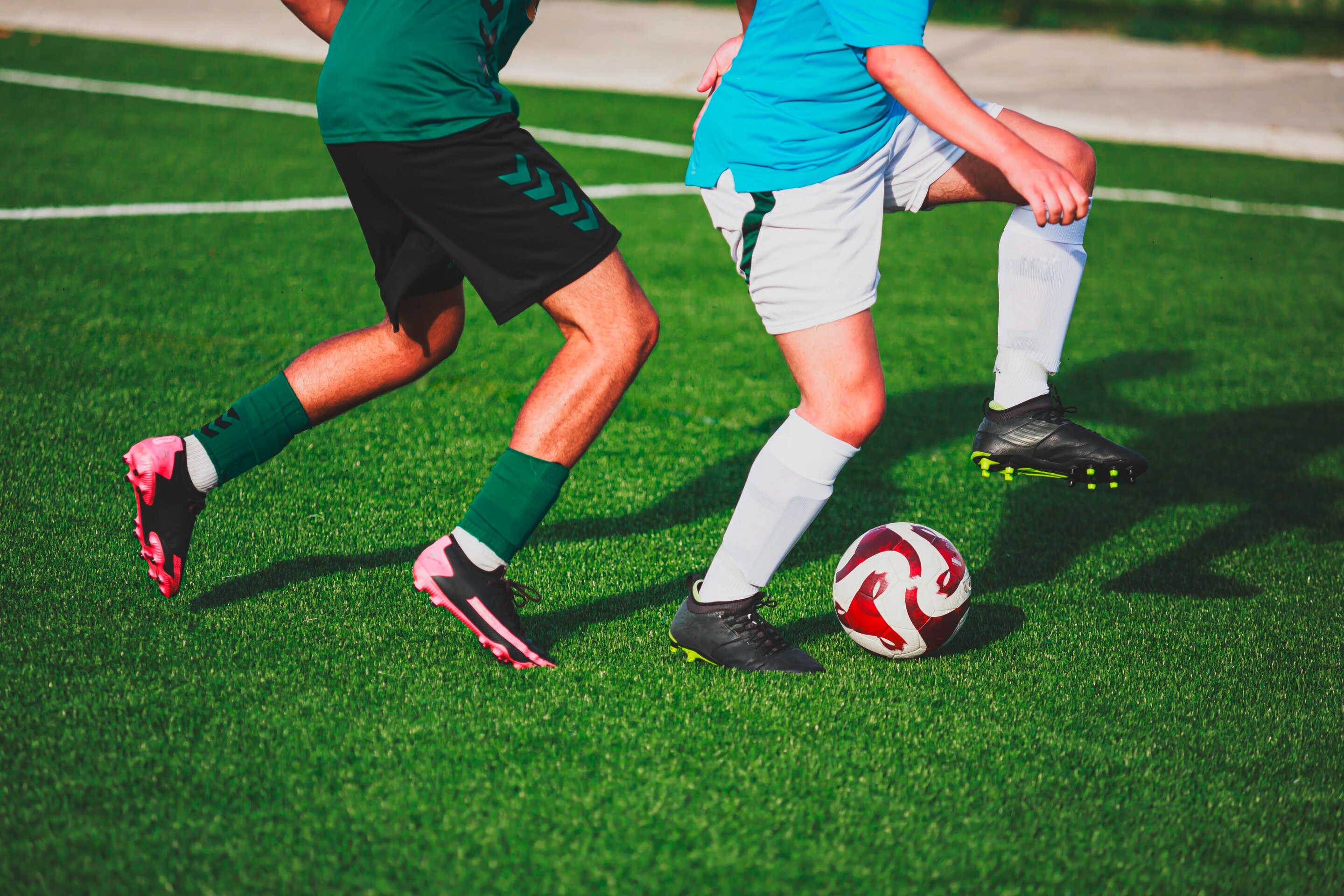 pria Asia sedang bermain sepak bola di lapangan rumput.