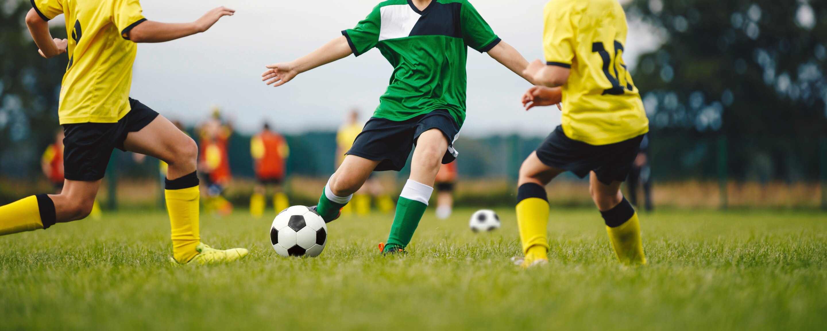 sekelompok orang dari tim berbeda sedang bermain sepak bola di lapangan rumput.