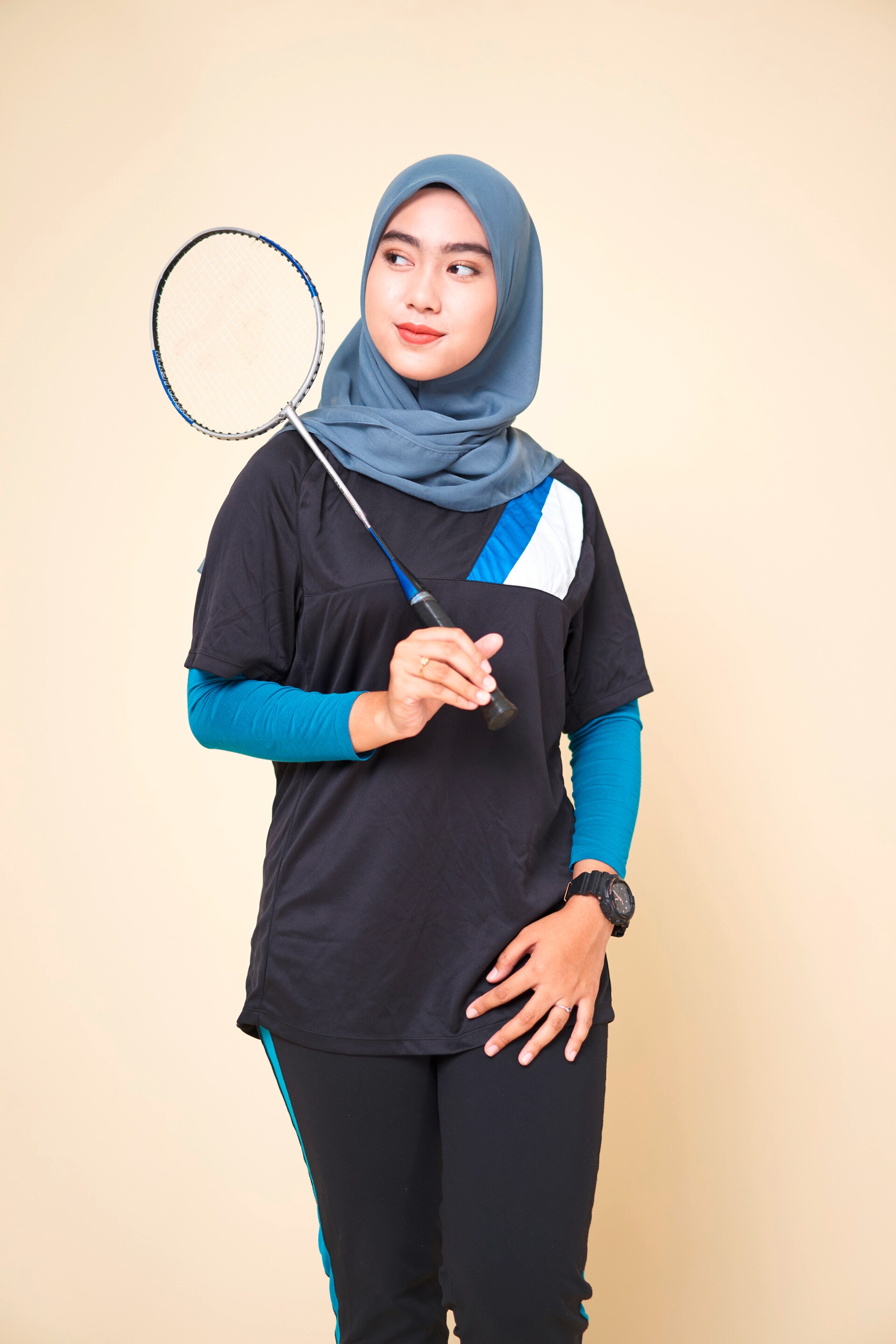 wanita berhijab sedang memegang raket badminton.