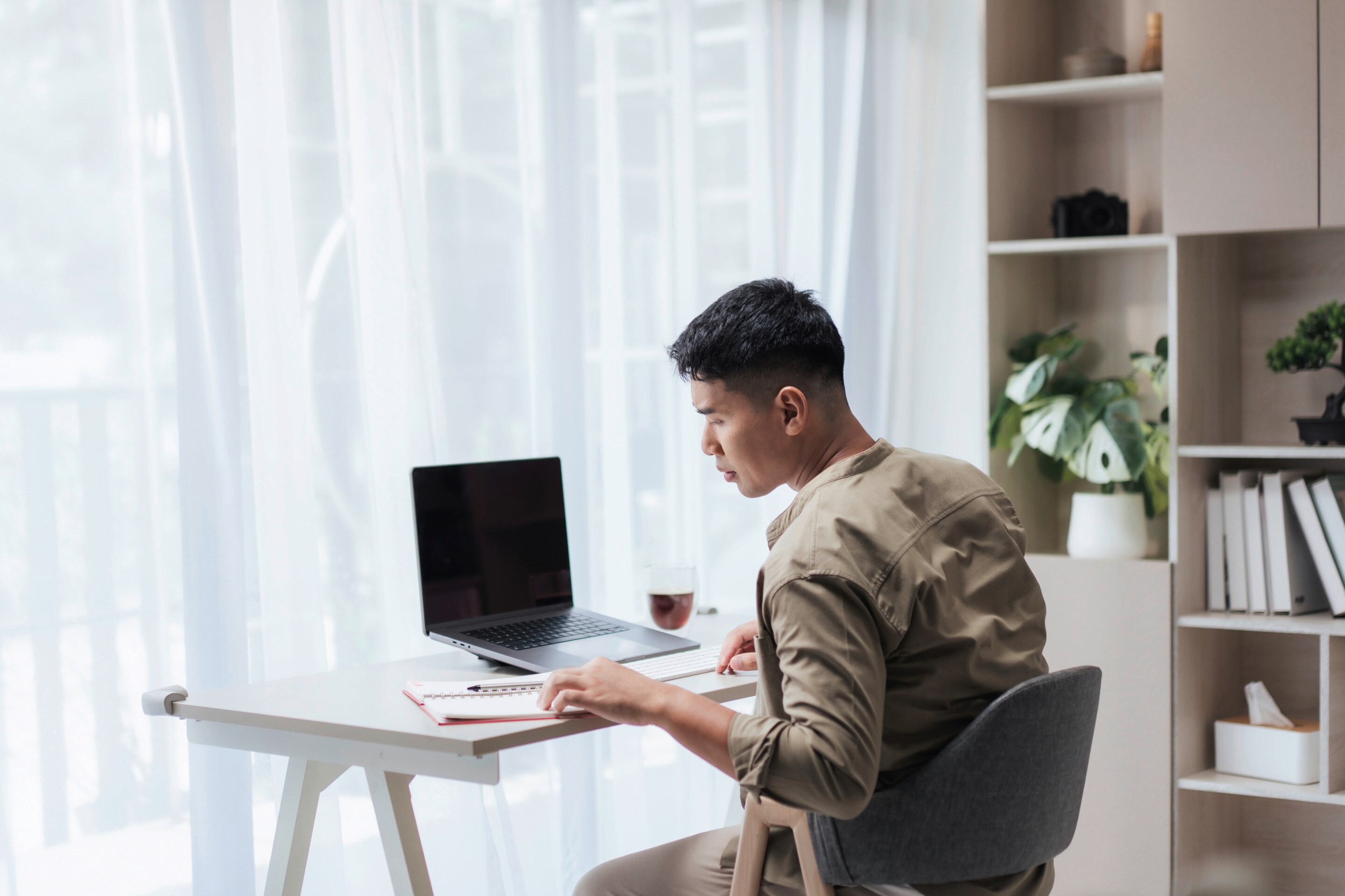 Man working on laptop by the window.