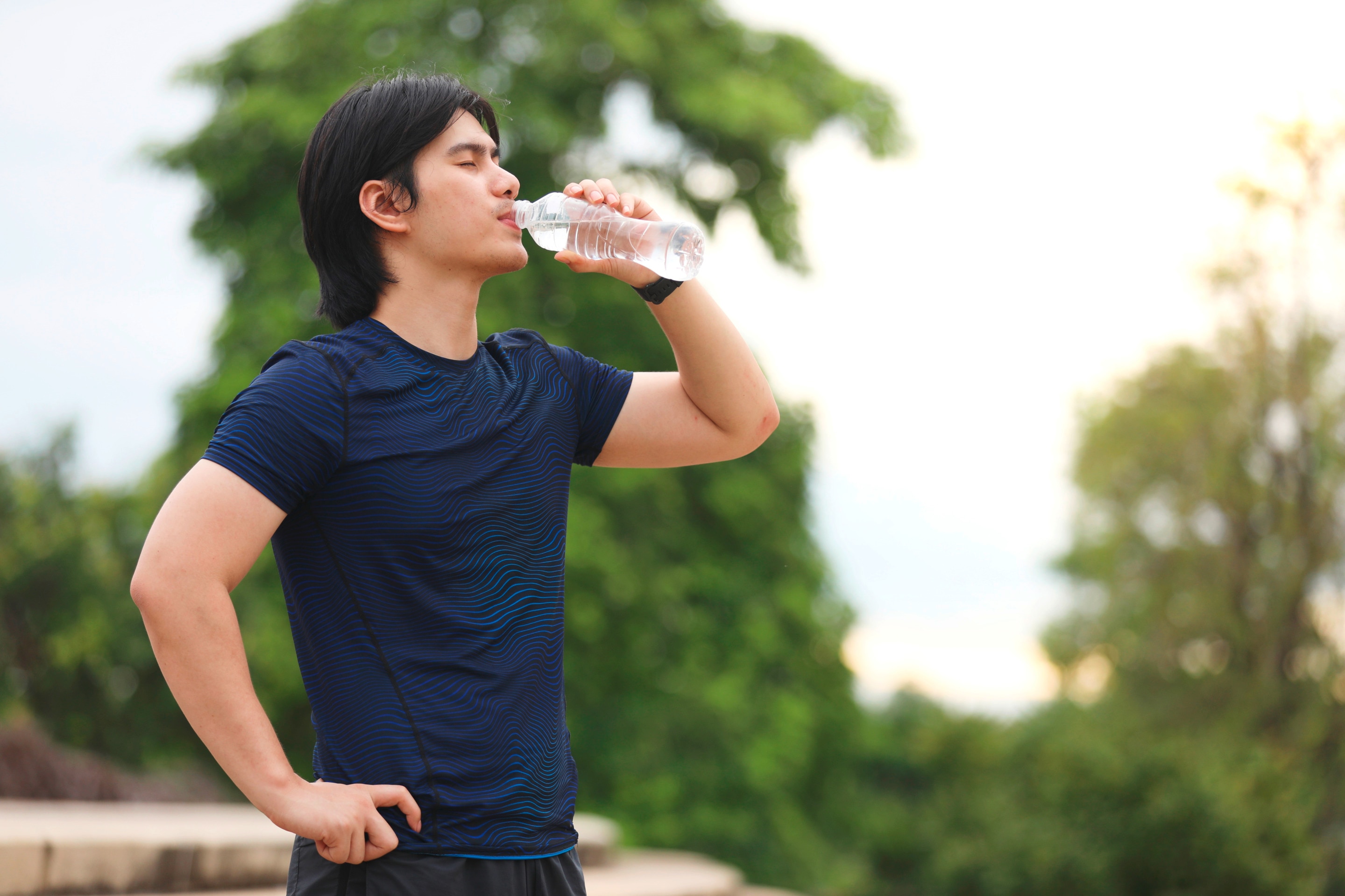 Man outdoors drinking water from a bottle.