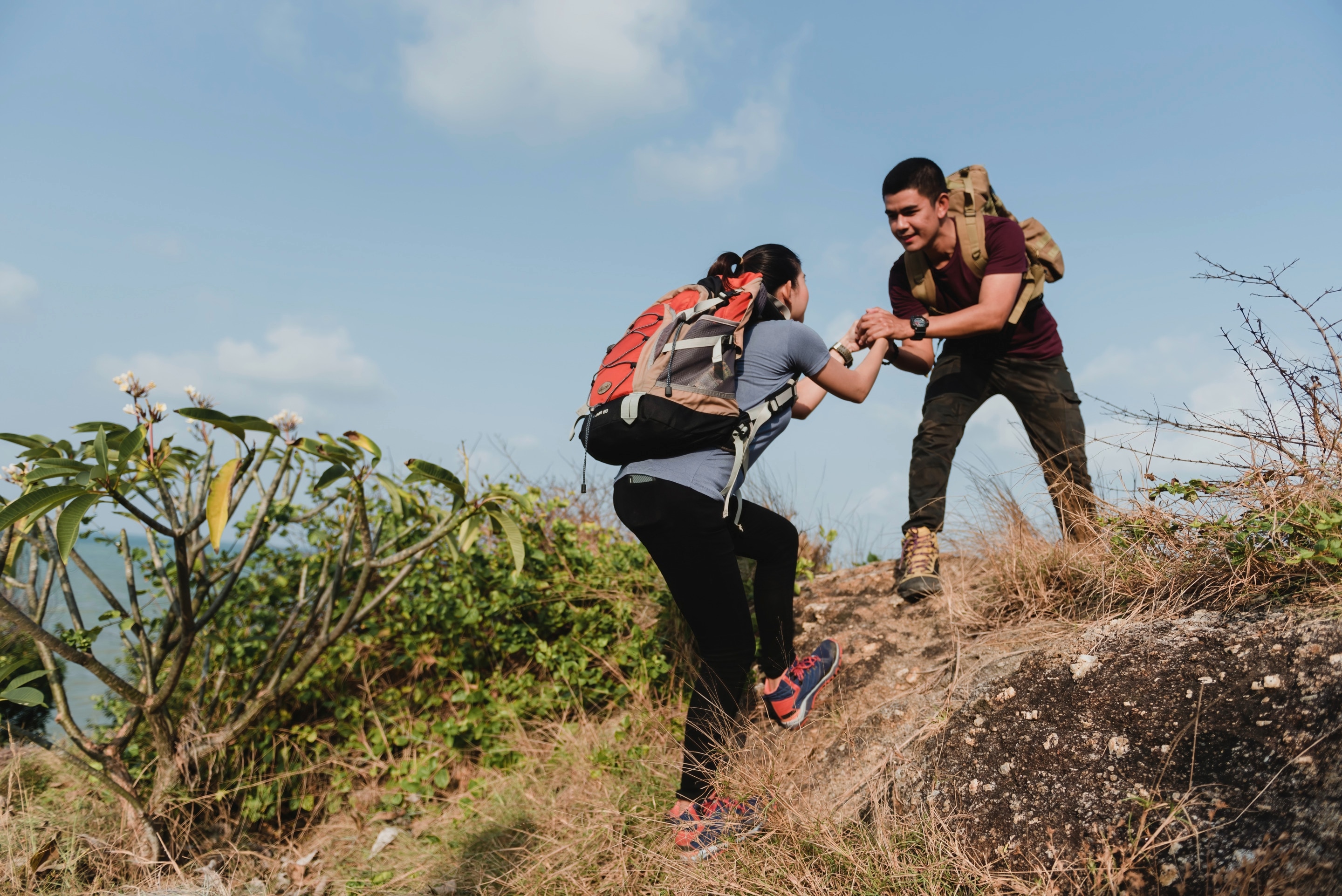 Man helping a woman up on a hike.