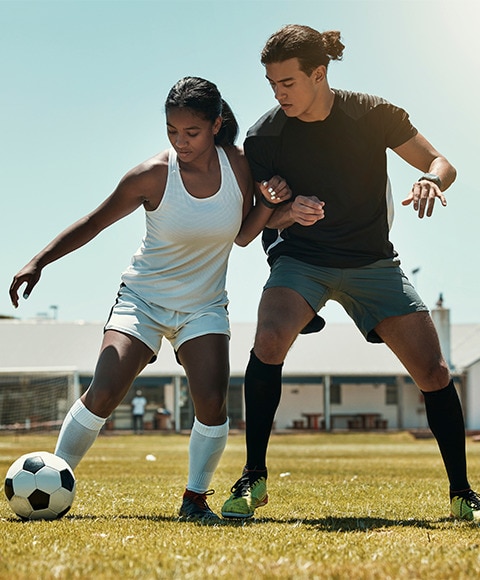 Two friends playing soccer outdoors experiencing both heat sweat and stress sweat