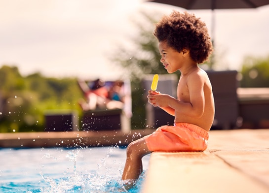 Child enjoying a Popsicle® next to the pool in summer