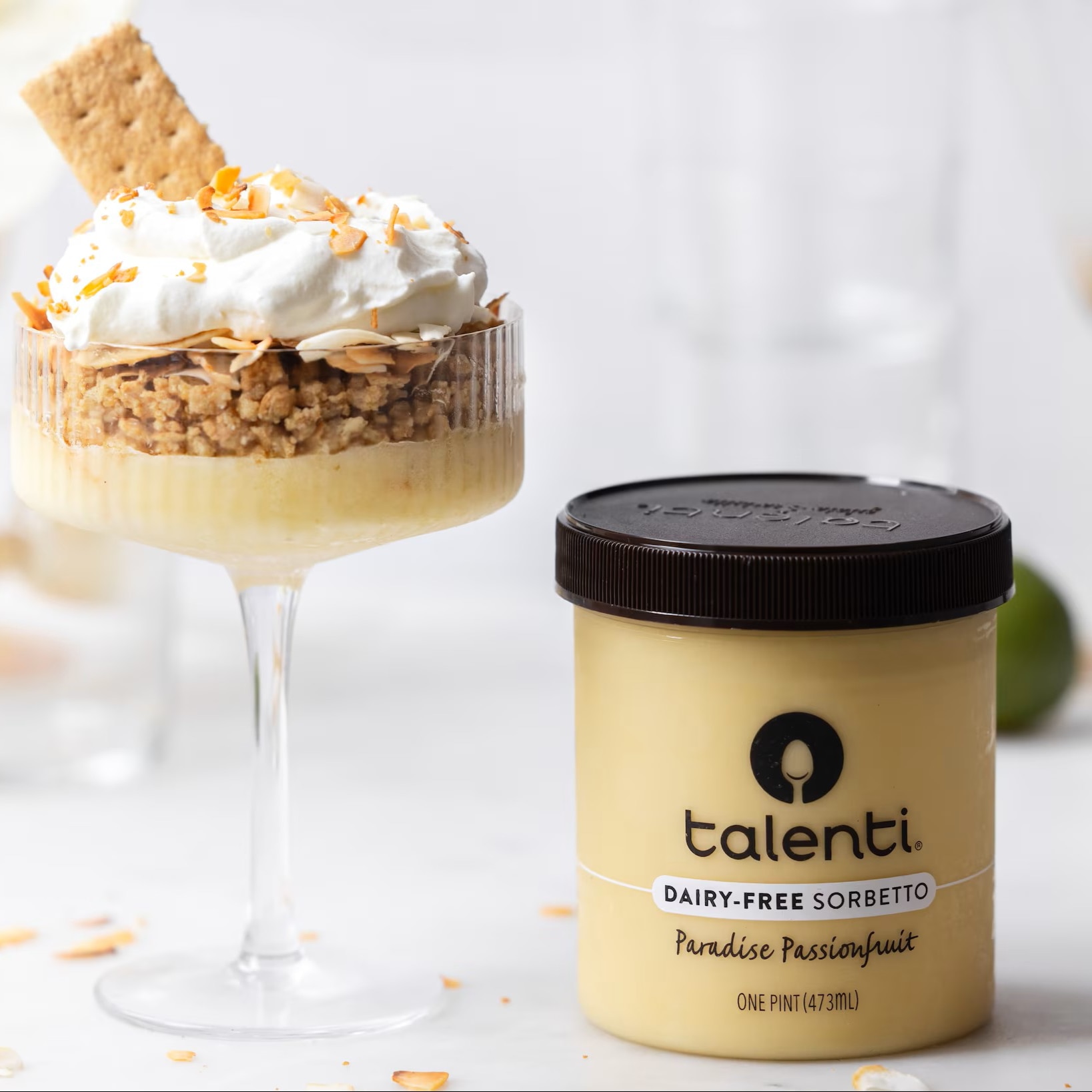 Paradise Passionfruit Parfait in a cocktail glass with a pint of Talenti Paradise Passionfruit Sorbetto next to it