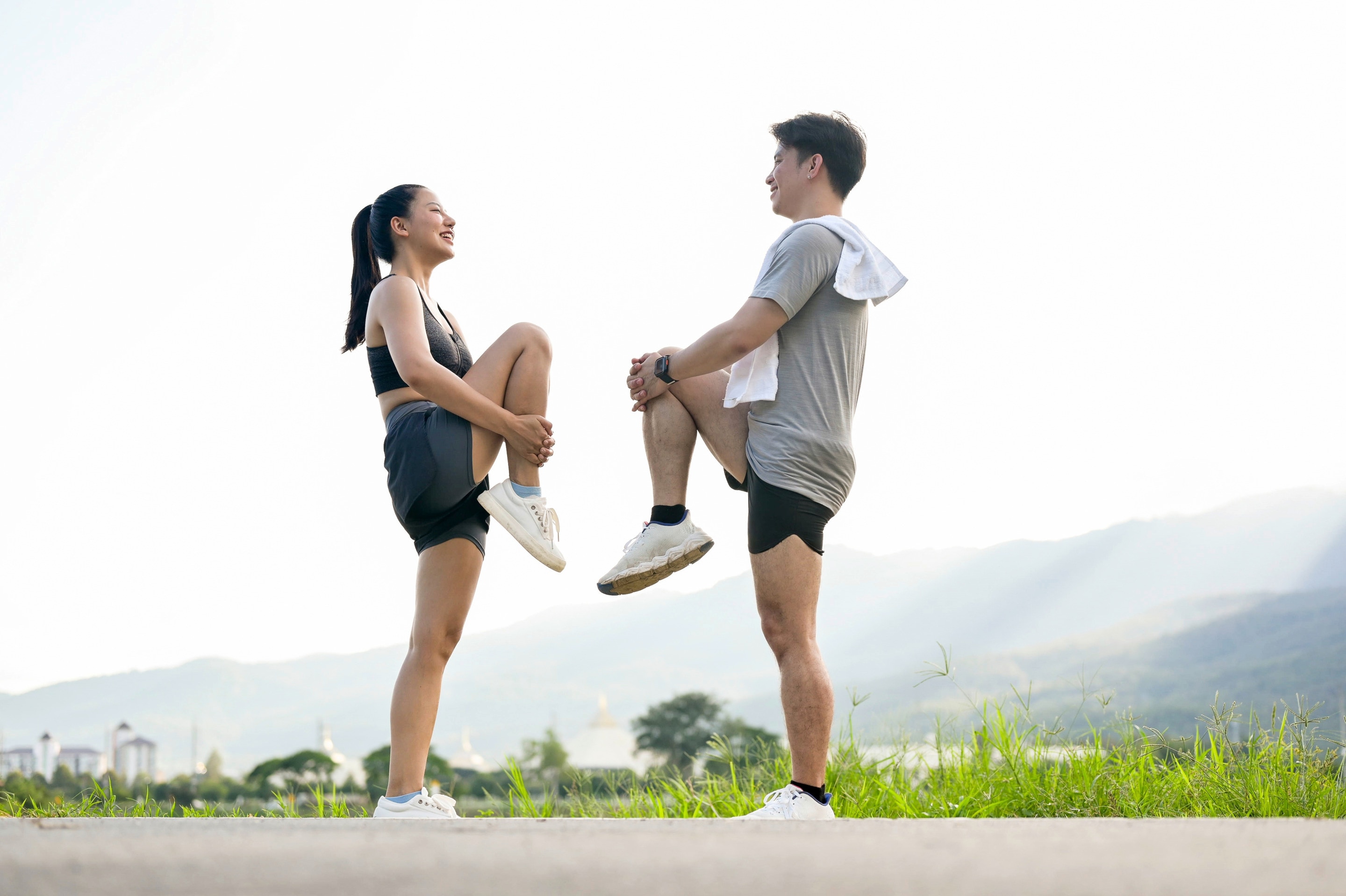 Seperti yang terlihat di foto, ada pria dan wanita Asia sedang melakukan stretching sebelum olahraga.