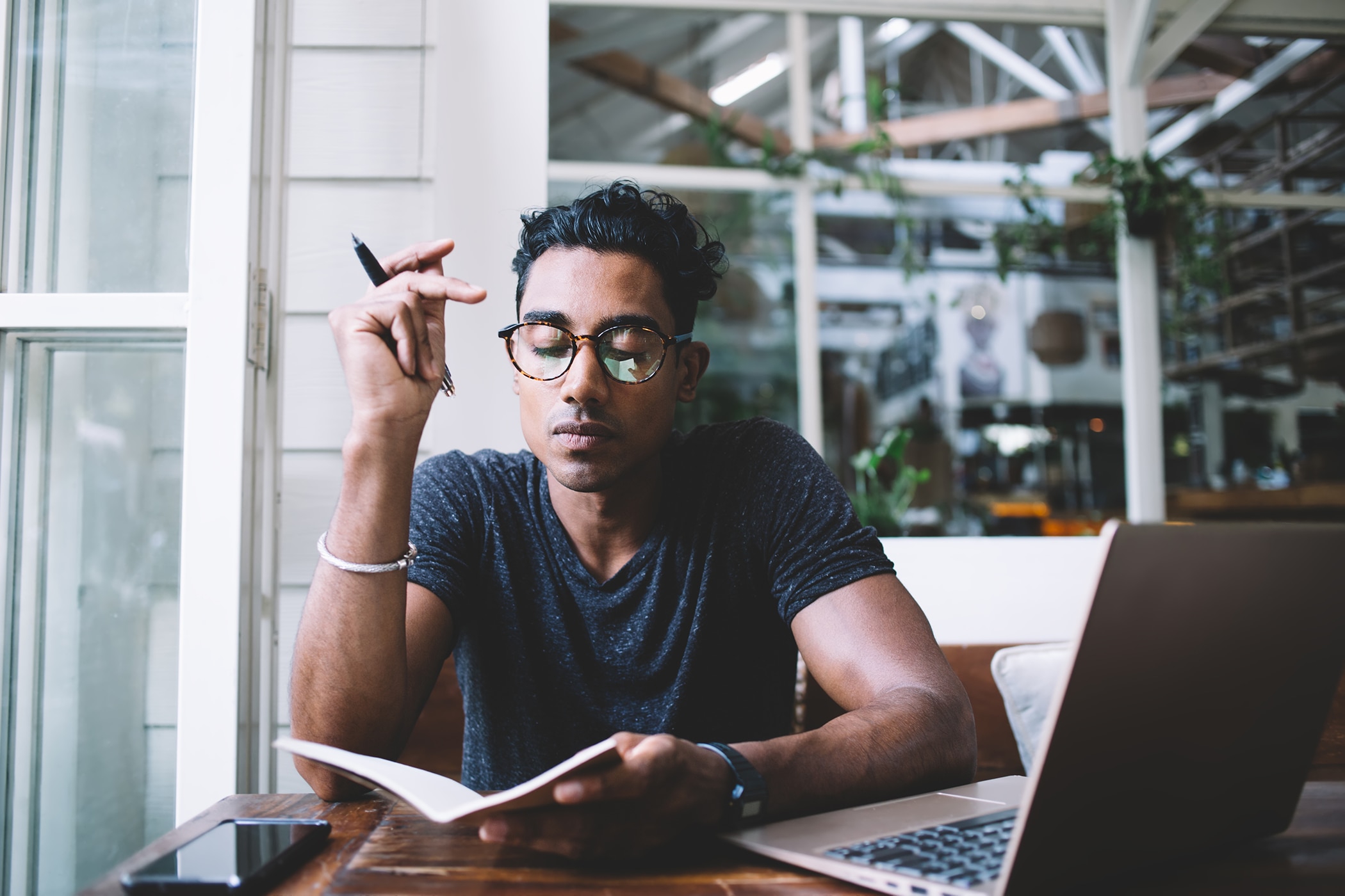 Young man sitting in a coffee shop, writing his goals down