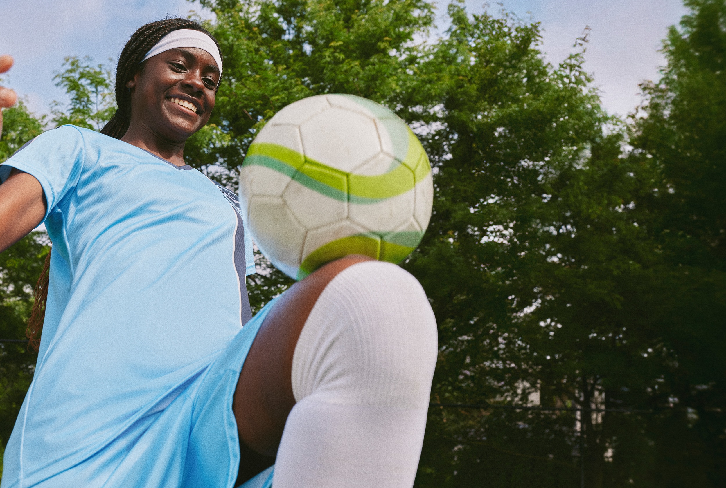 Girl kneeing football on field 