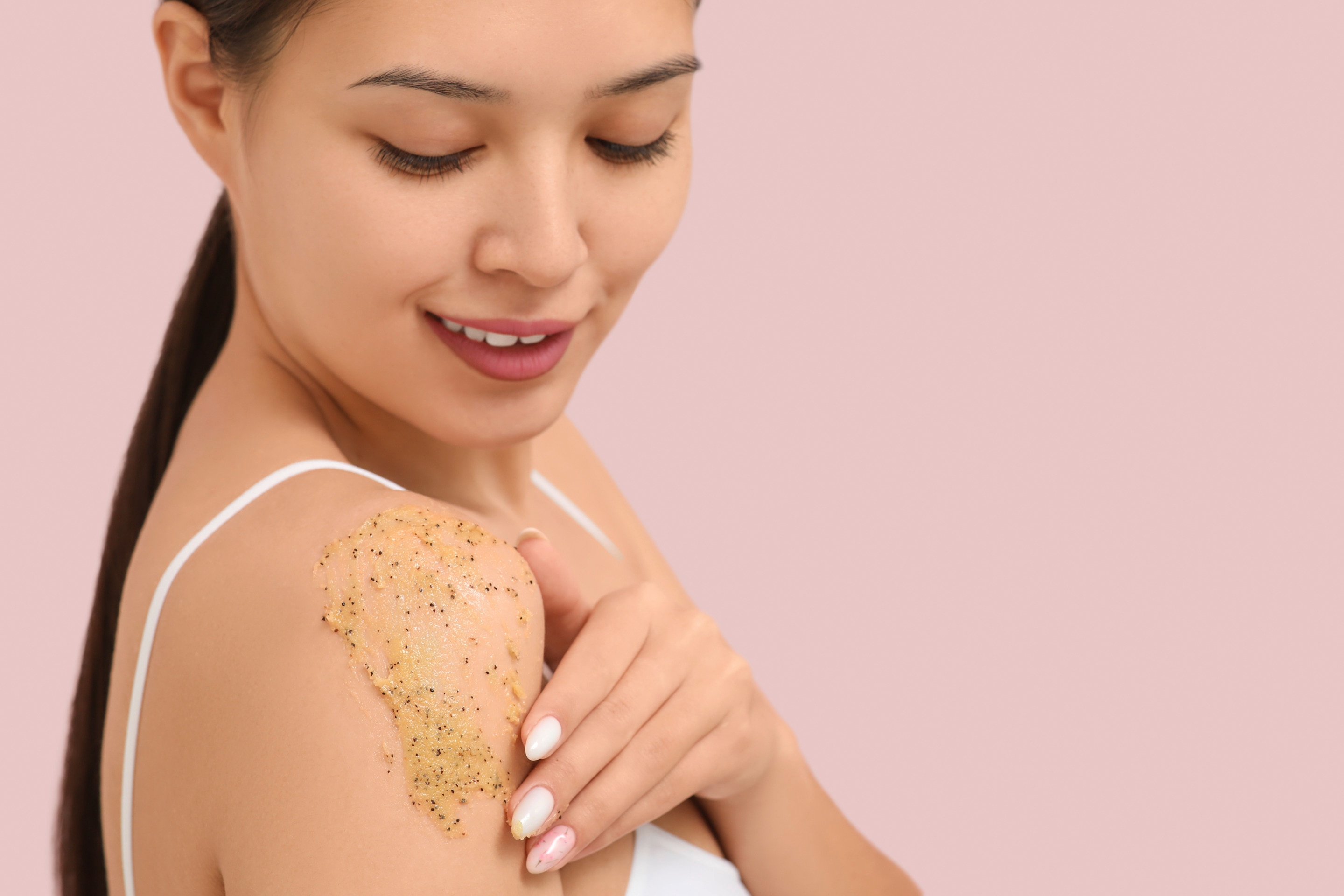 Seperti yang terlihat pada foto, seorang wanita sedang mengaplikasikan body scrub pada bahu 
