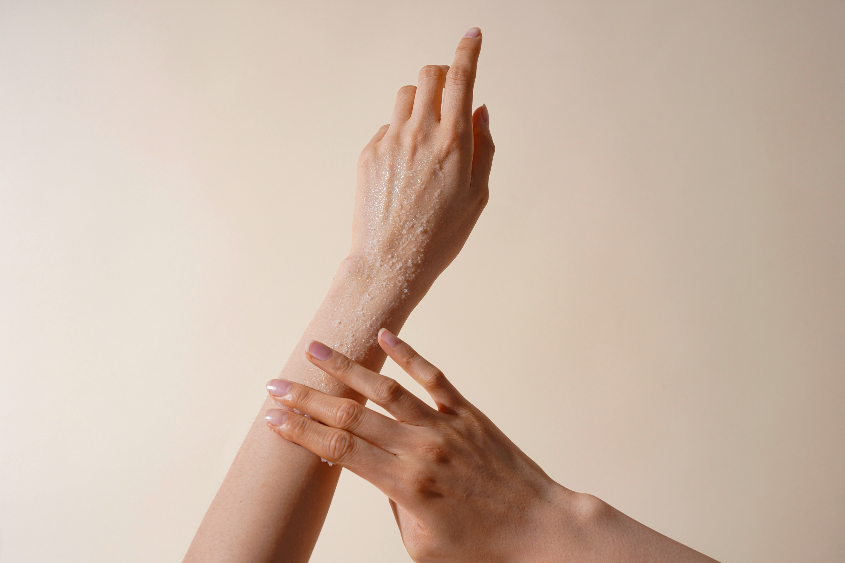 Seperti yang terlihat pada foto, seorang wanita sedang mengaplikasikan body scrub di tangan 