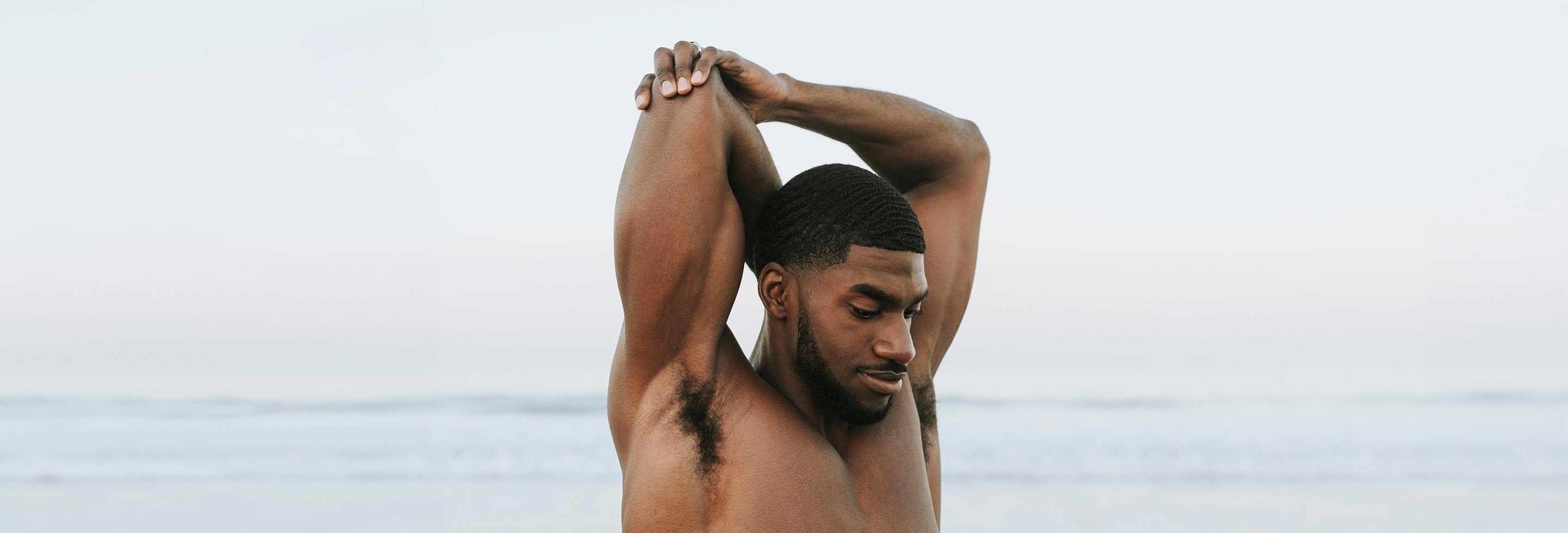 Man stretching and exposing his underarms with no sign of discoloration under armpits 