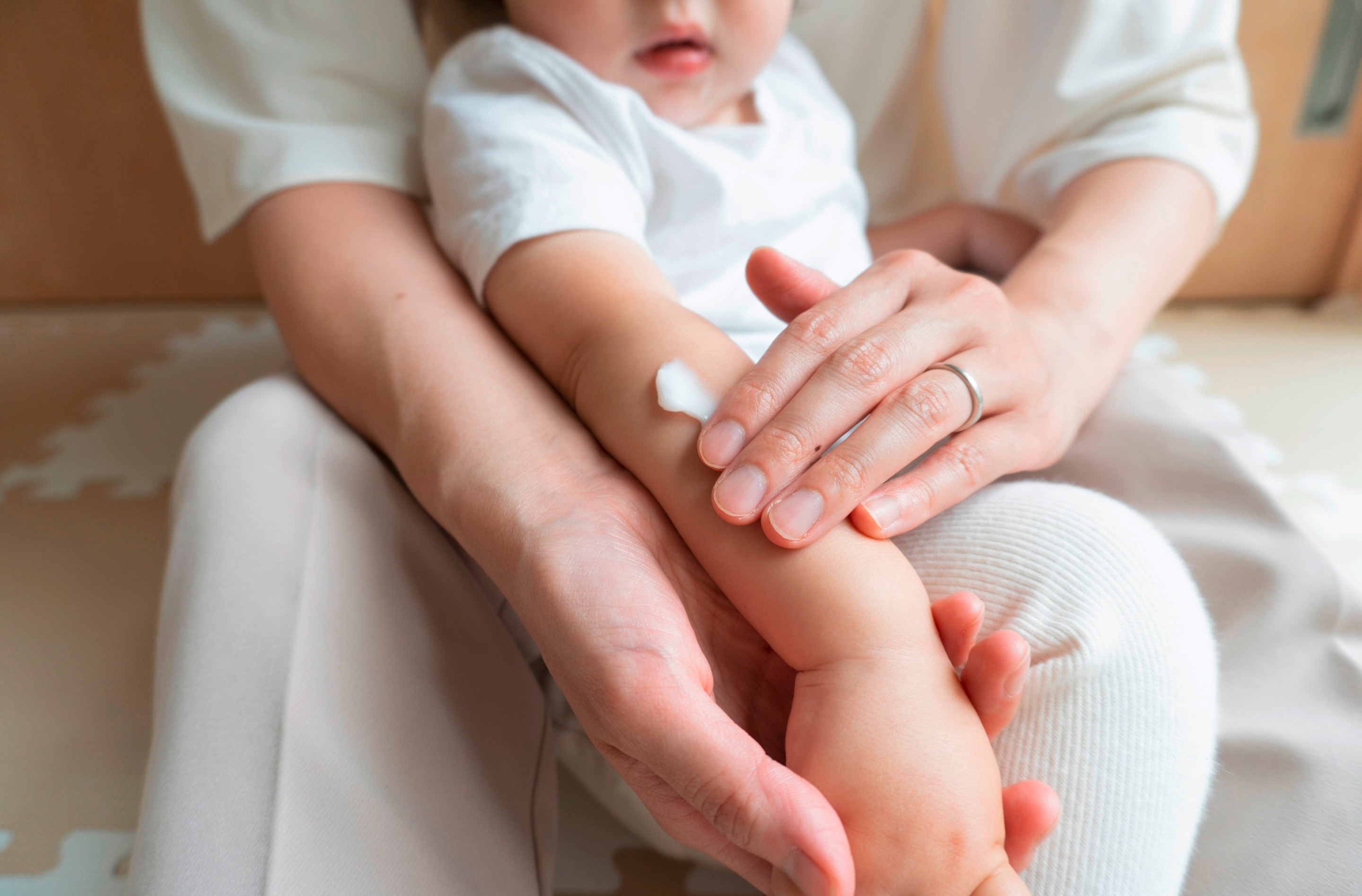 ada ibu mengoleskan lotion pada kulit kaki bayi untuk membantu menjaga kelembapan dan melindungi kulit sensitif dari iritasi atau dermatitis kontak.