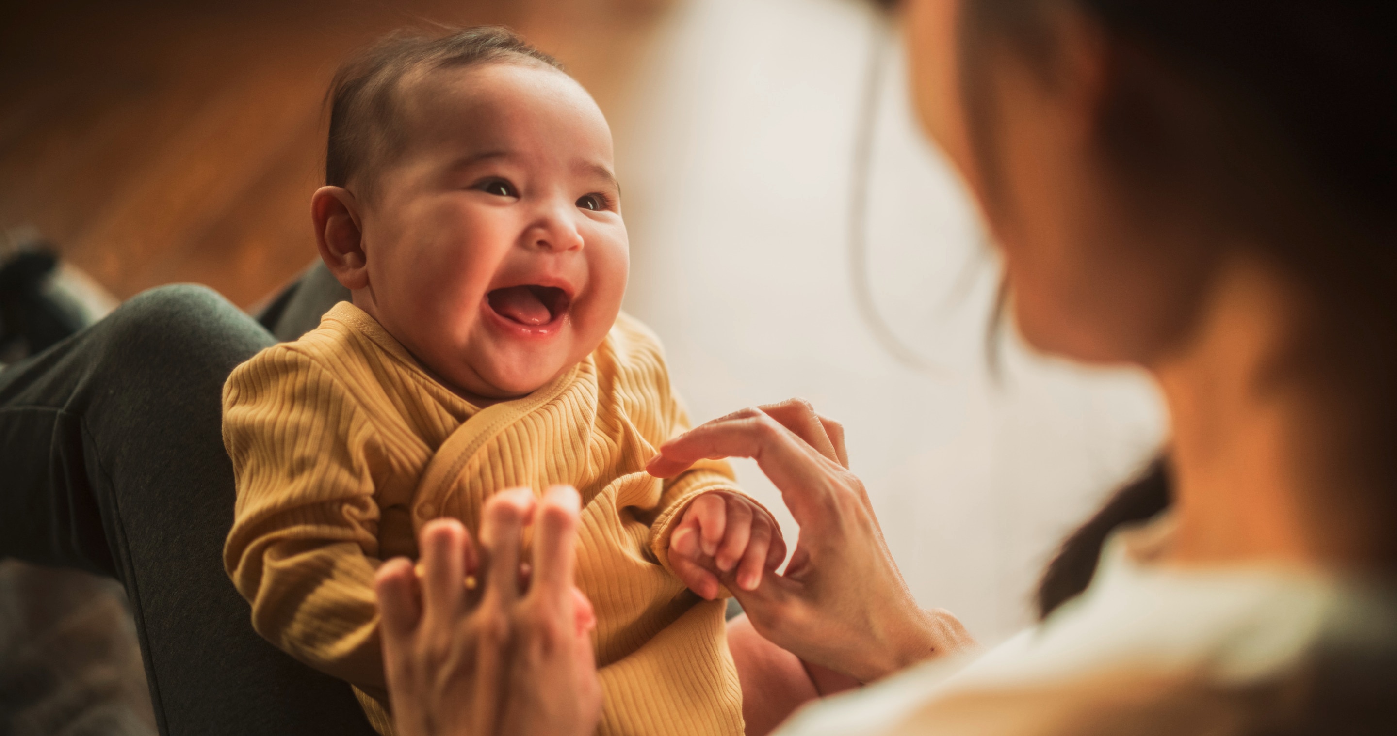 bayi usia 6 bulan yang sedang tersenyum pada ibunya.