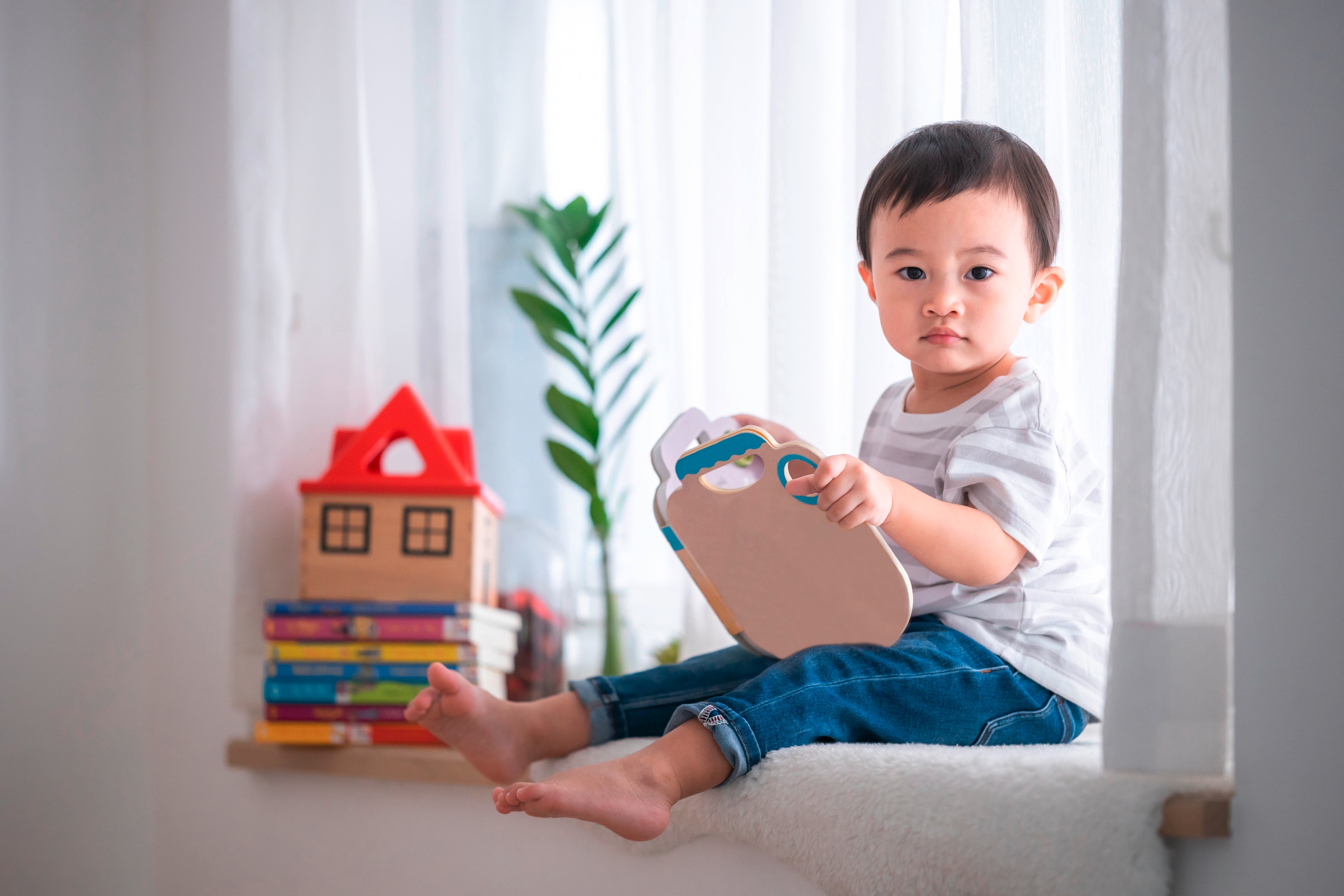 ada anak balita sedang duduk di tepi jendela