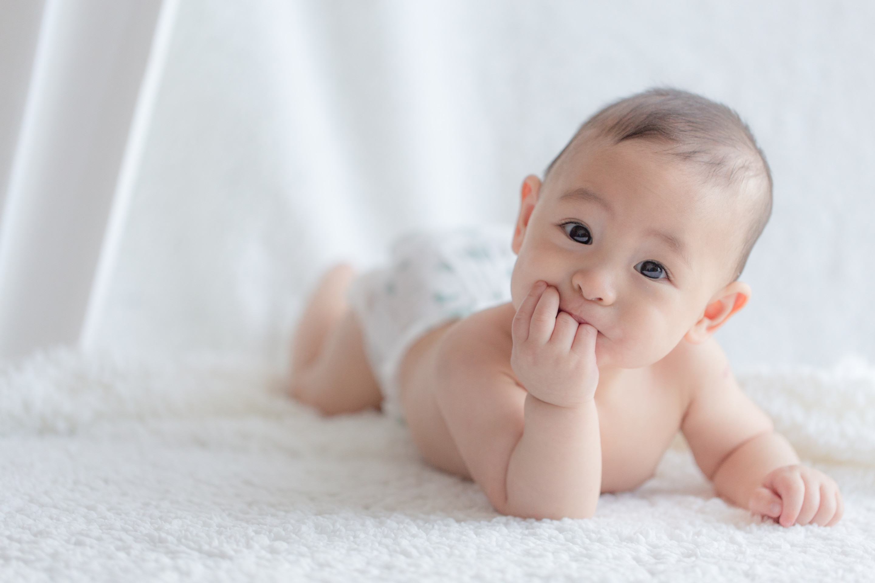 terlihat seorang bayi sedang tengkurap sambil tersenyum