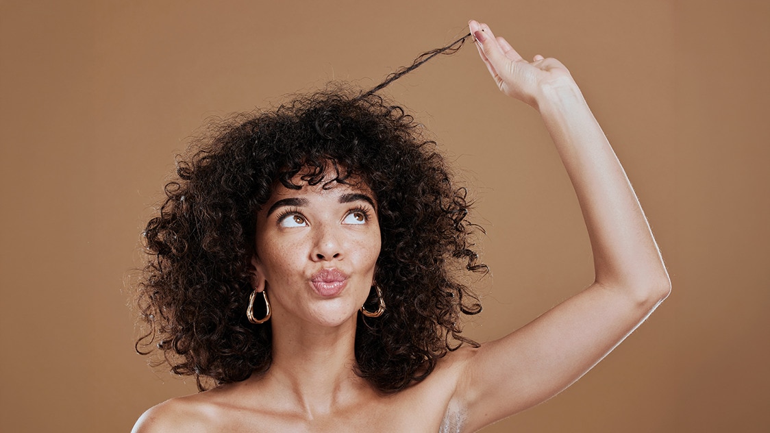 Woman with strong, resilient curls after repairing her hair from heat damage