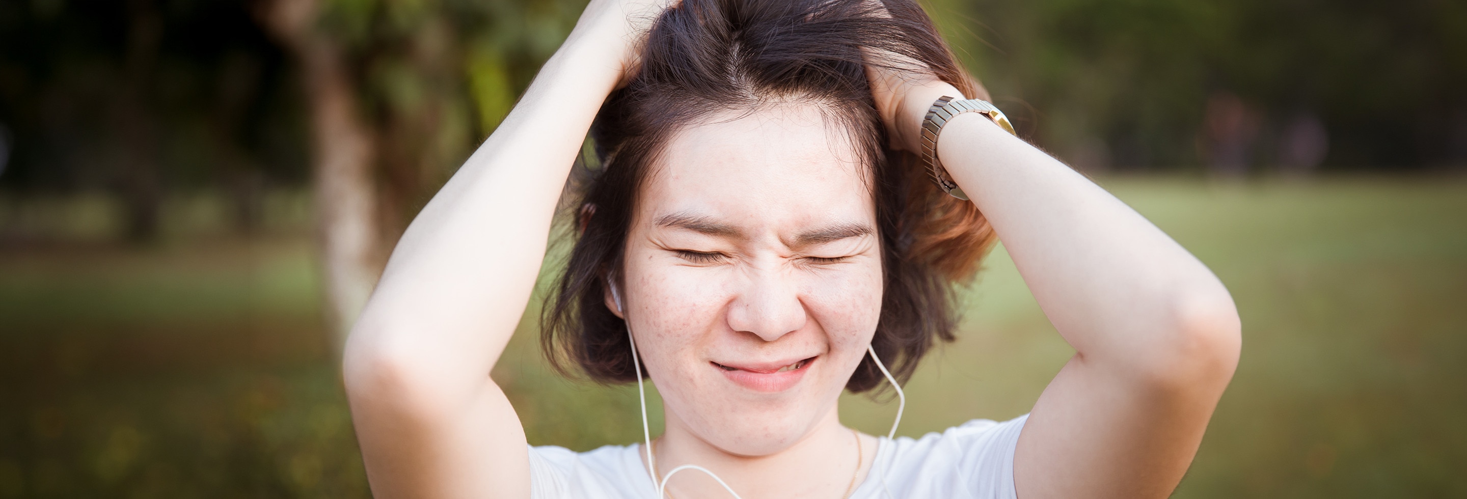 Woman with hands in her hair looking frustrated because of dry scalp