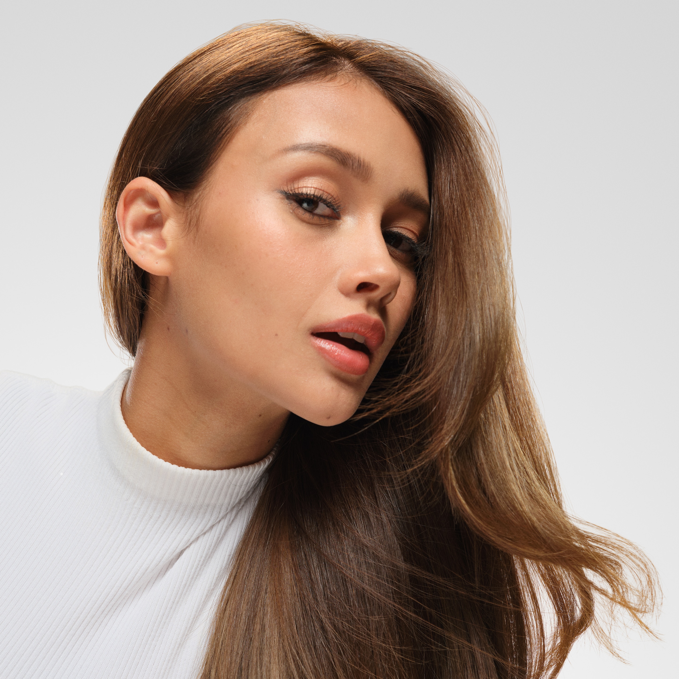 A hairdresser using a heat styling tool on a section of a model's hair