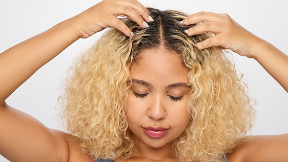 Afro-Latina woman inspecting her hair roots to find a way to stop her scalp from itching