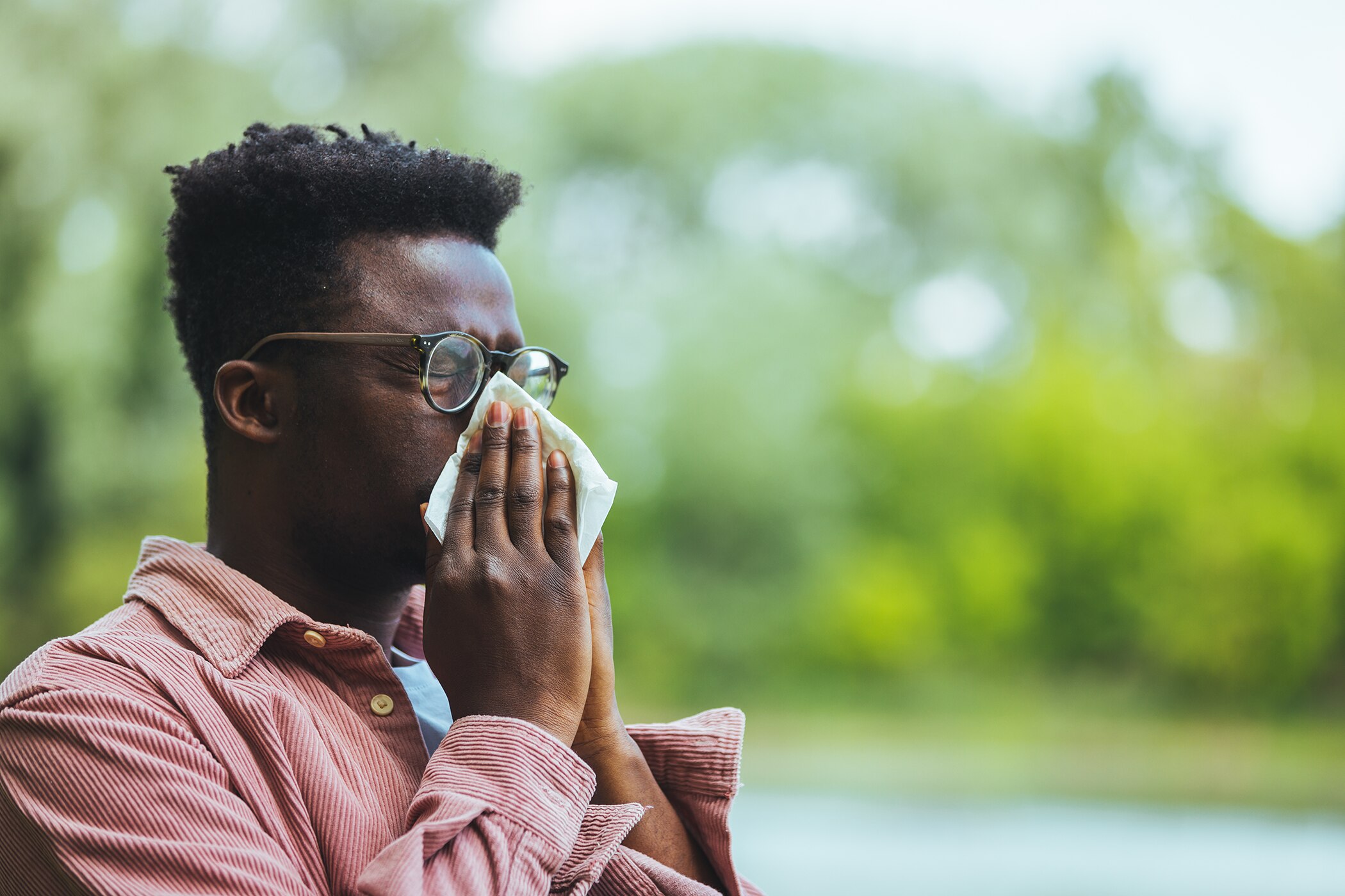 Man sneezing in the park during allergy season