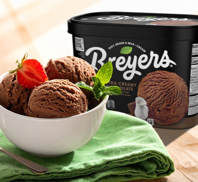 Bowl of chocolate ice cream next to a tub of Breyers Chocolate Ice Cream in a casual home setting
