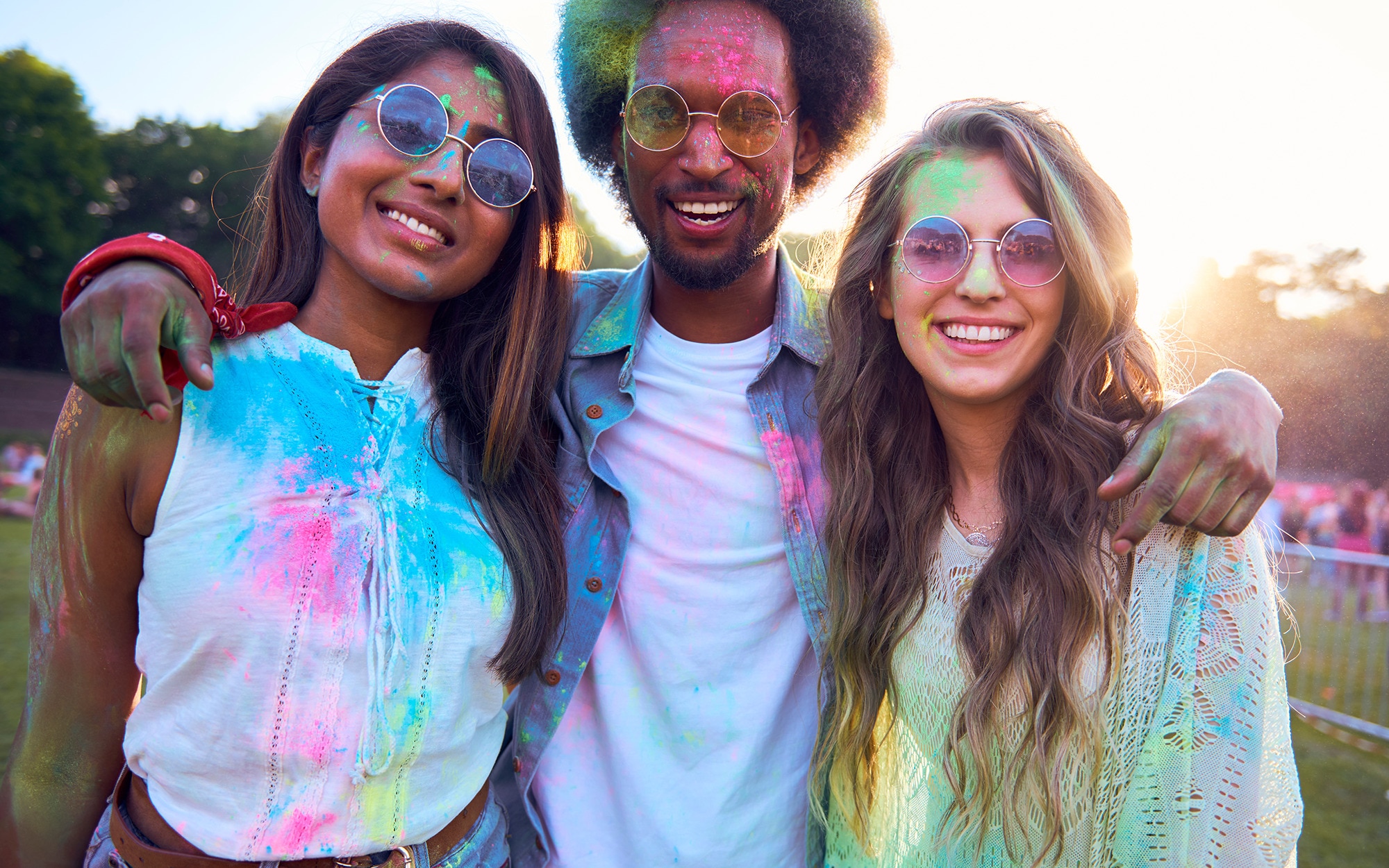 Woman with sunglasses and loose, tousled hair holding standing with her friends at a festival