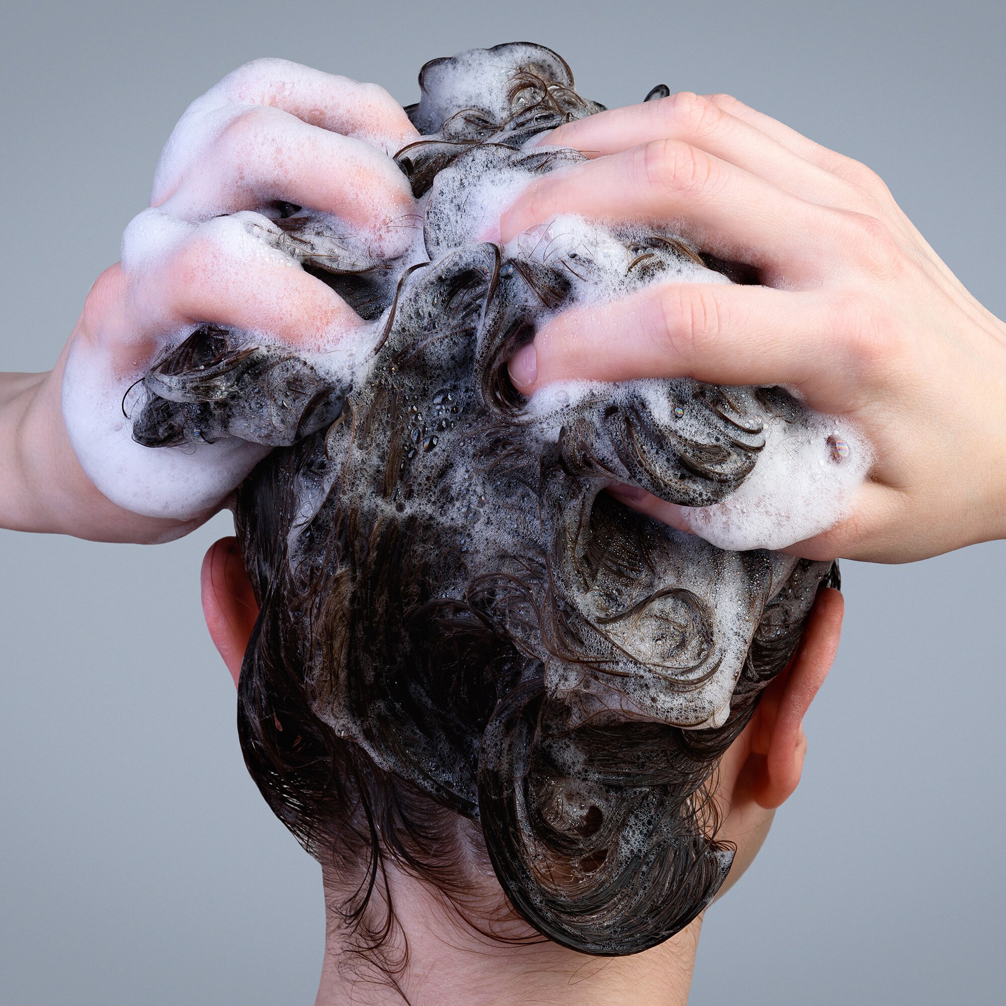Back view of a woman with dark hair washing her hair.