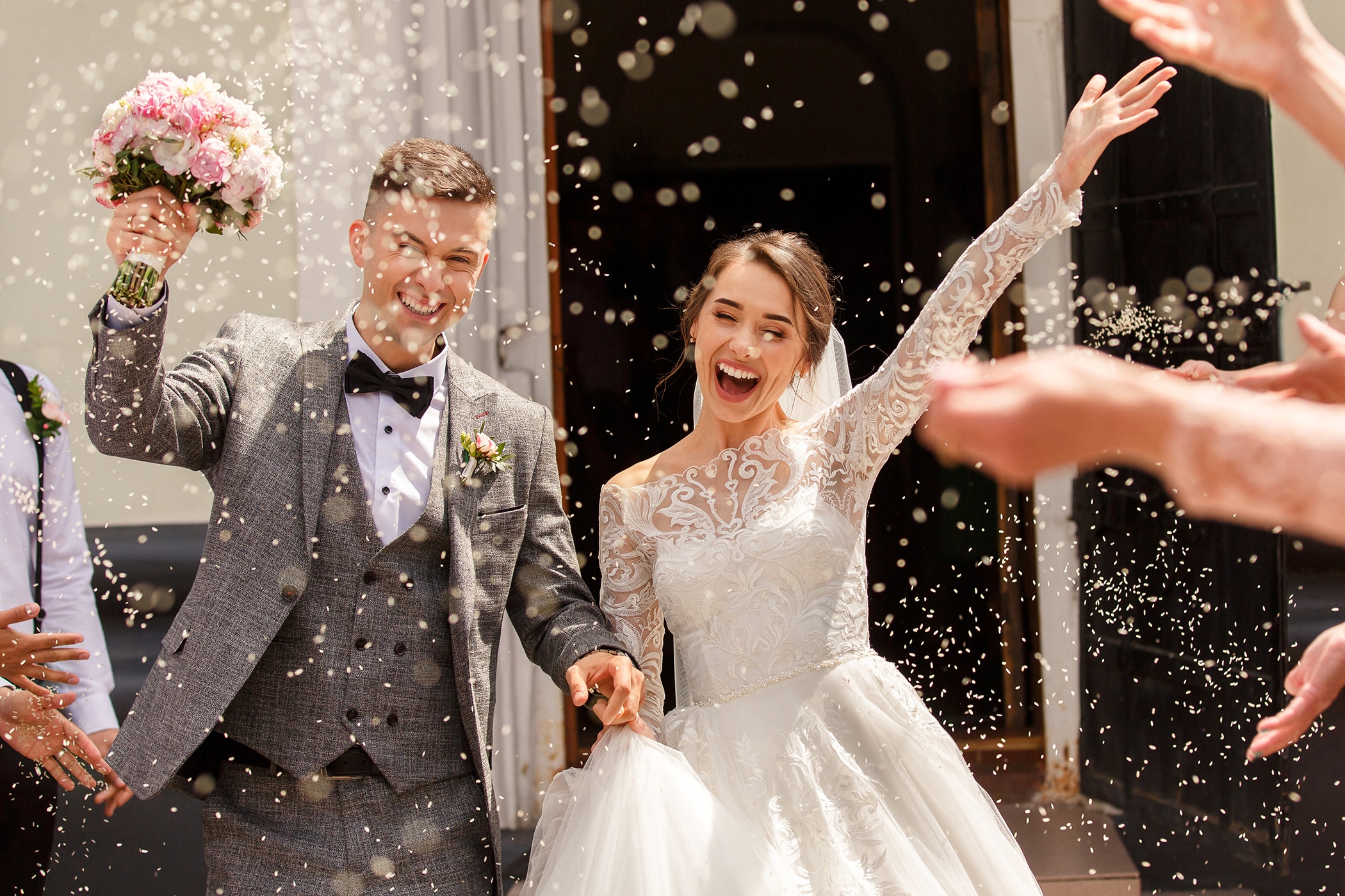 Bride and Groom at their wedding with arms raised with no sign of stress sweat while wearing the best wedding day deodorant&nbsp;