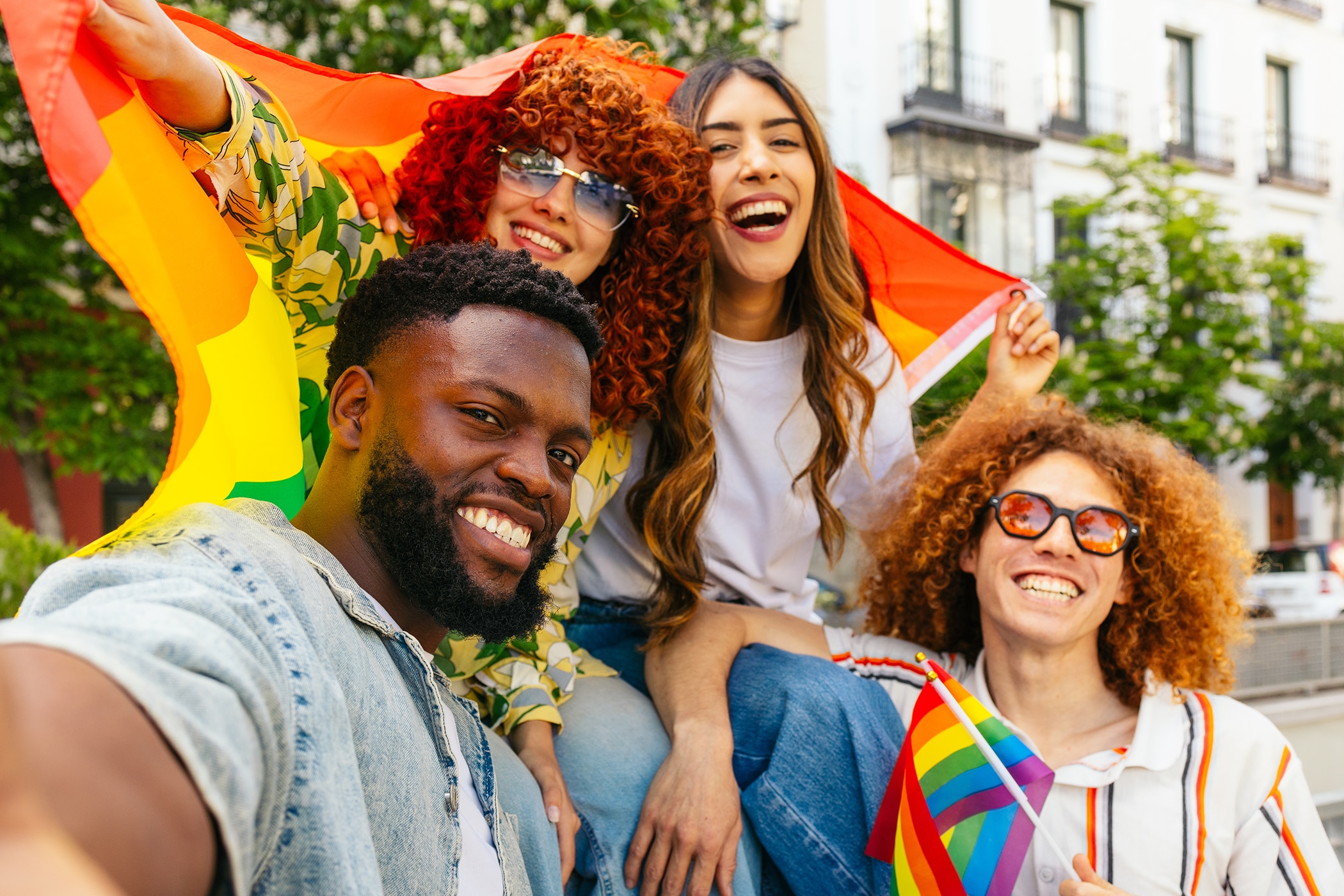 Group of LGBTQIA+ friends waving a Pride flag at a Pride event