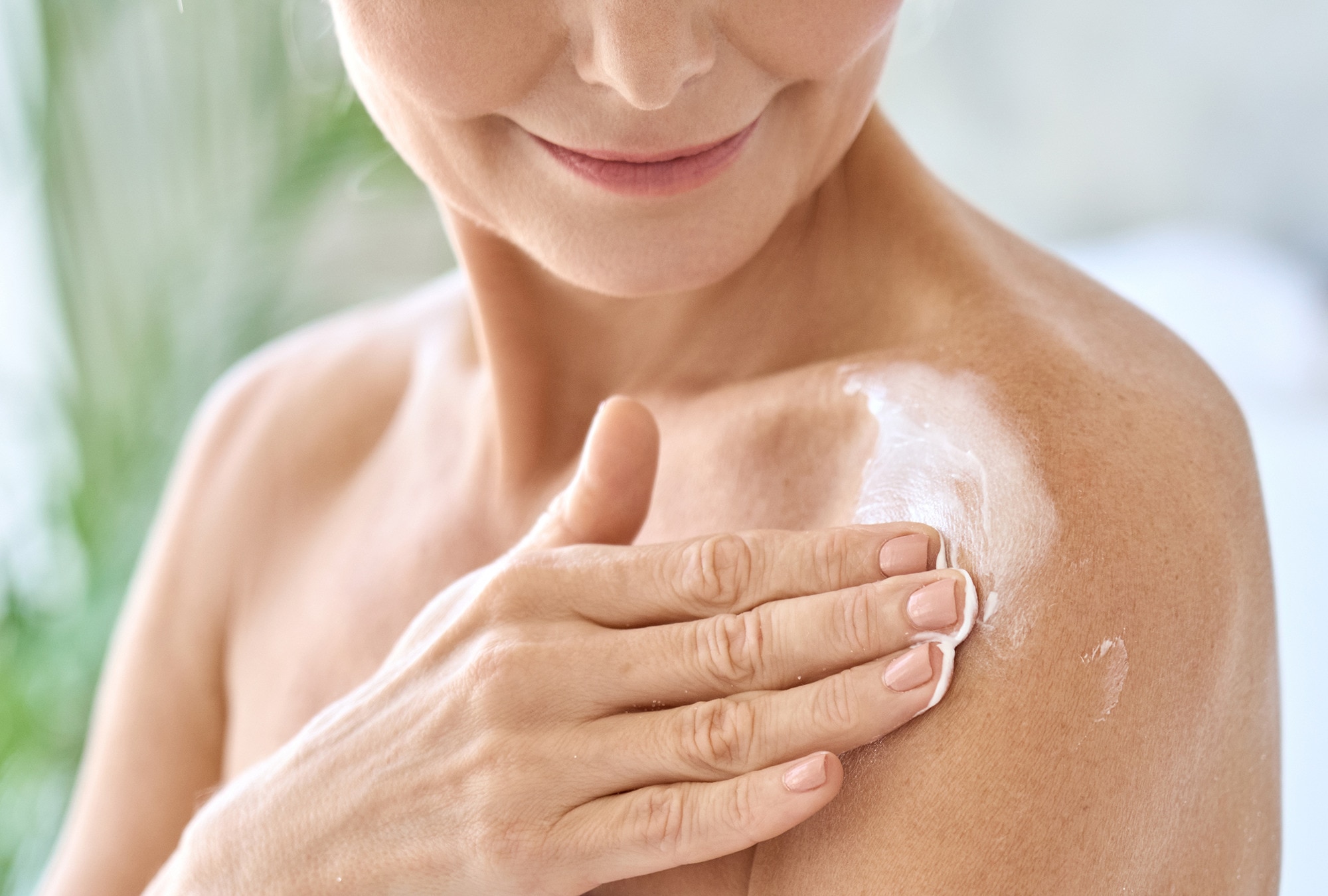 Woman applying body-firming lotion to help tighten and firm her body skin