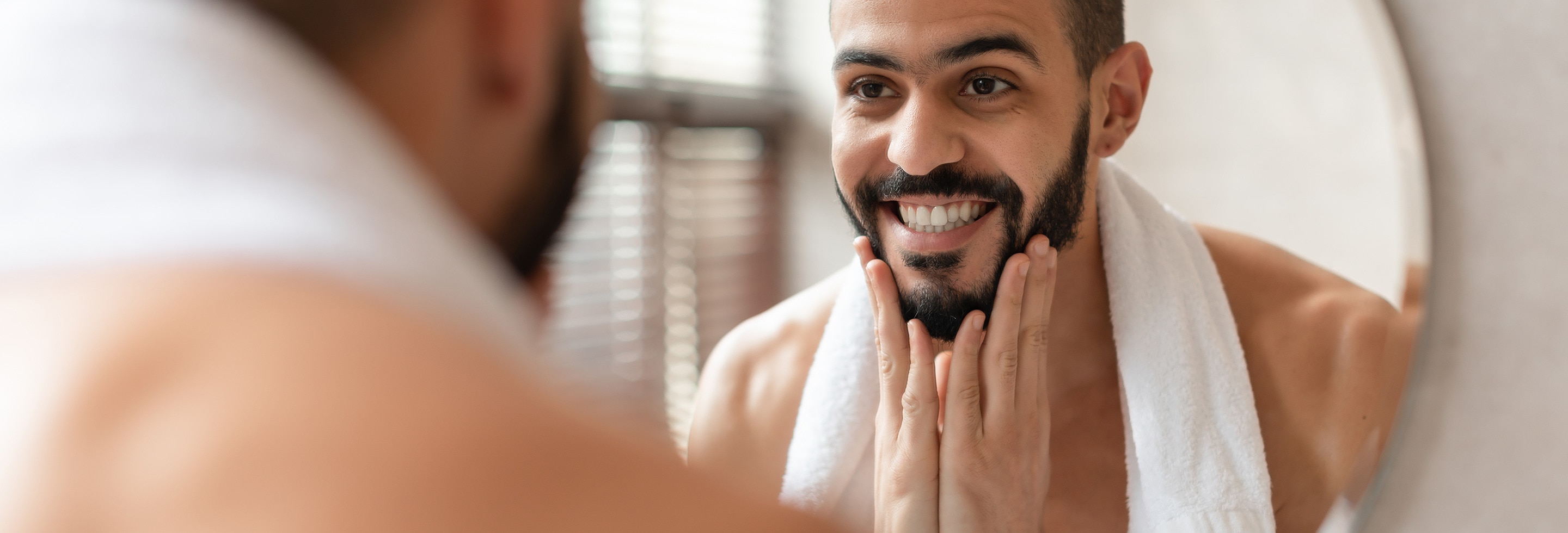 Man looking at himself in the mirror after hydrating his skin&nbsp;