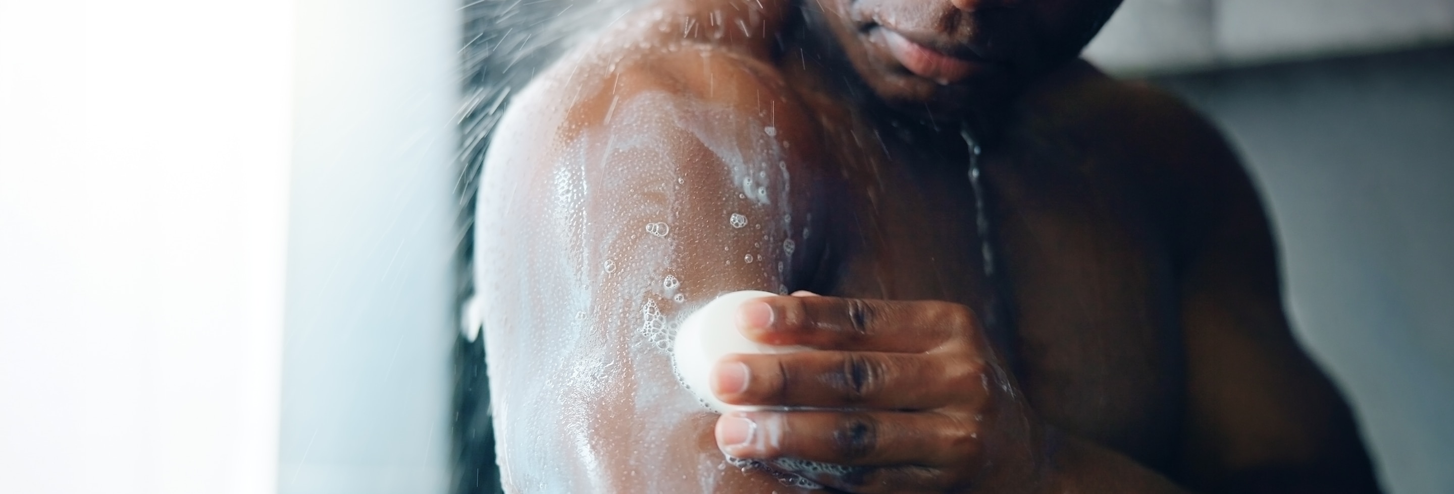 Man using Dove Men+Care cleansing bar in the shower 