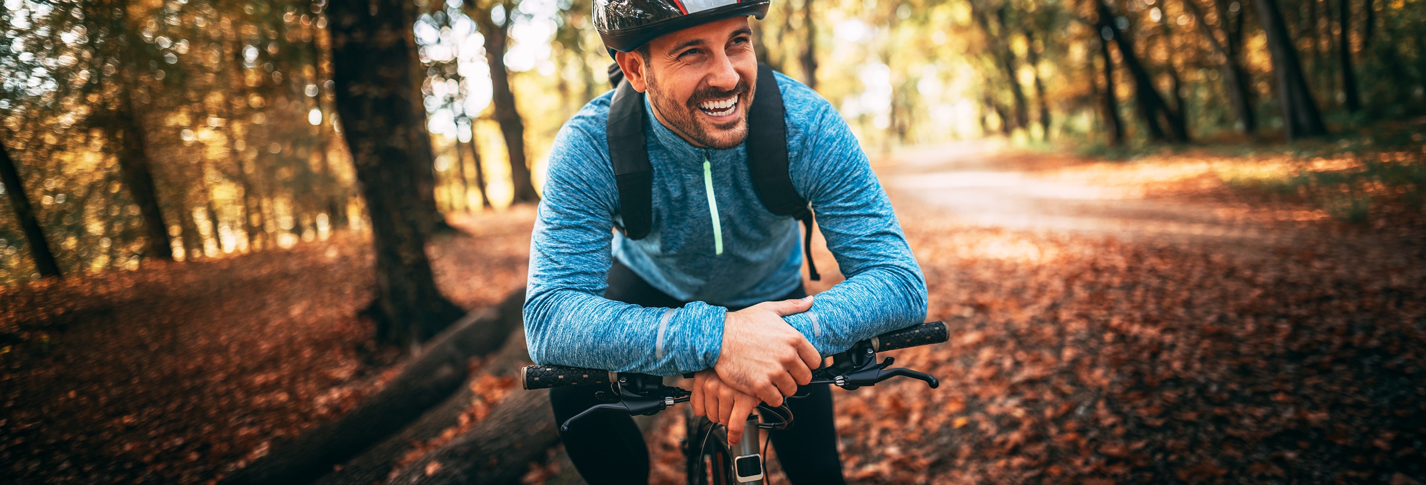 Happy man cycling through the forest contemplating whether to use deodorant or antiperspirant