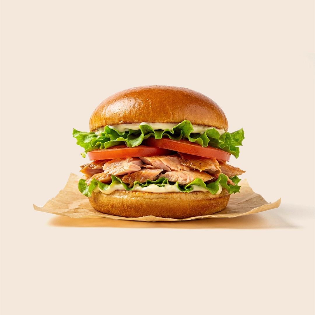 Flaky pan-seared trout sandwich on a brioche bun with lettuce, tomato, and mayo-based tartar sauce