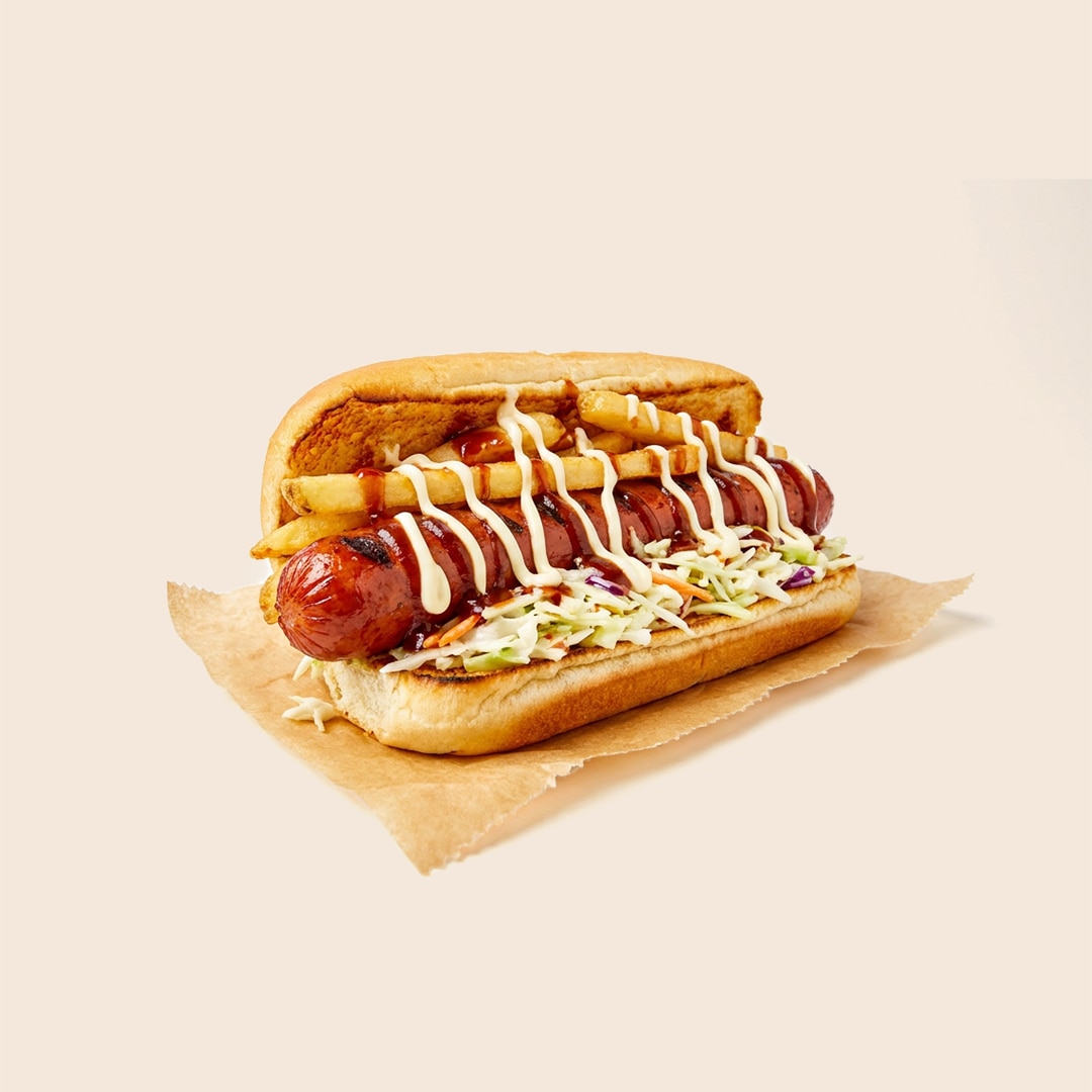 Ohio Polish Boy sandwich featuring a grilled sausage in a bun topped with mayo-based coleslaw, french fries, and barbecue sauce.