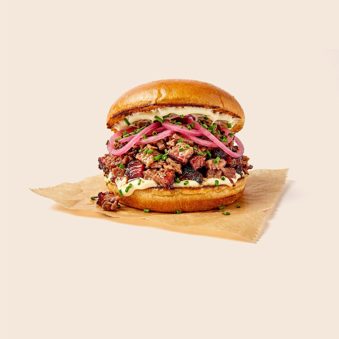 Texas chopped brisket sandwich topped with pickled red onions, mayo and chives on a brioche bun.