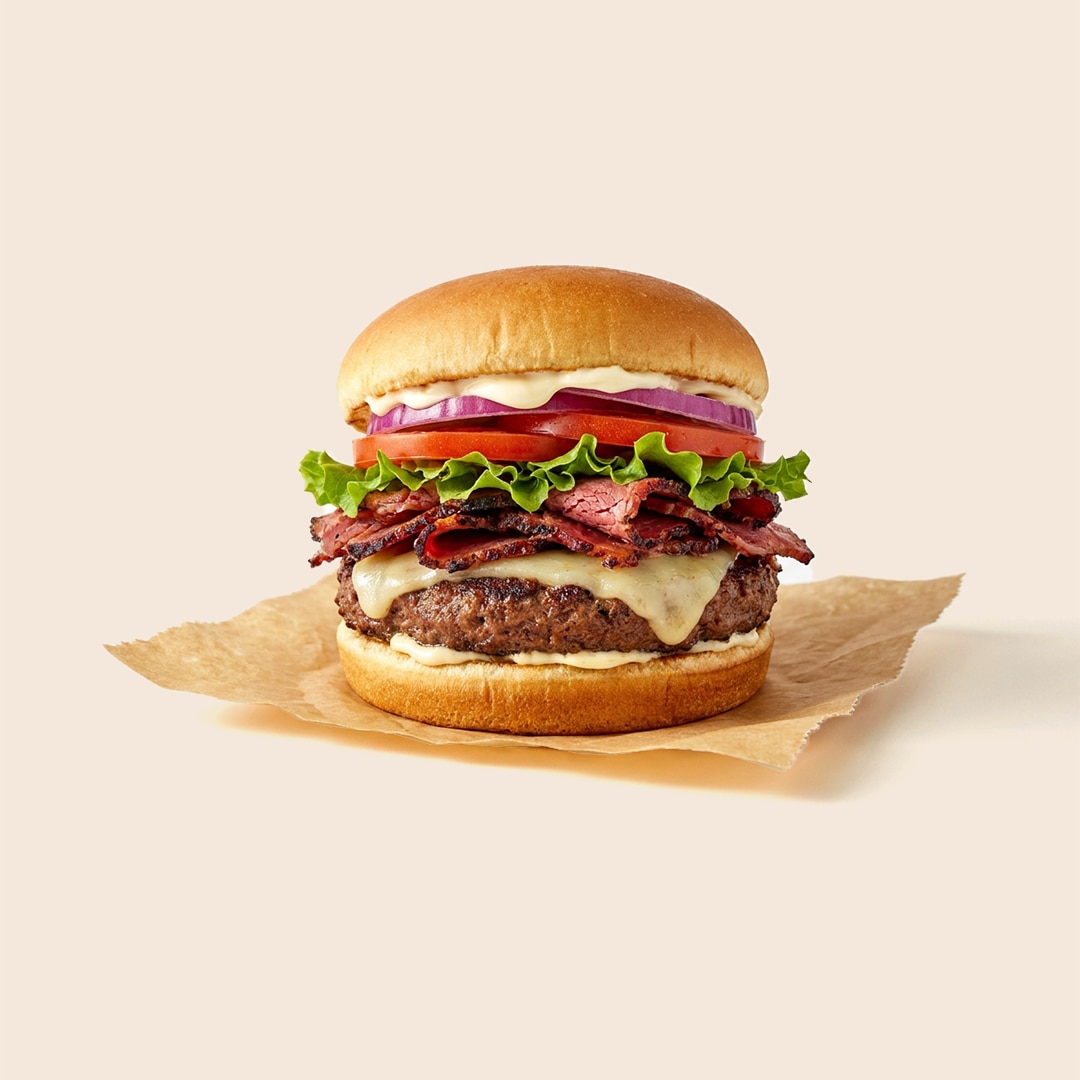 Utah-style pastrami burger featuring a beef patty topped with hot pastrami, Swiss cheese, lettuce, tomato, onion, and mayo-based fry sauce.