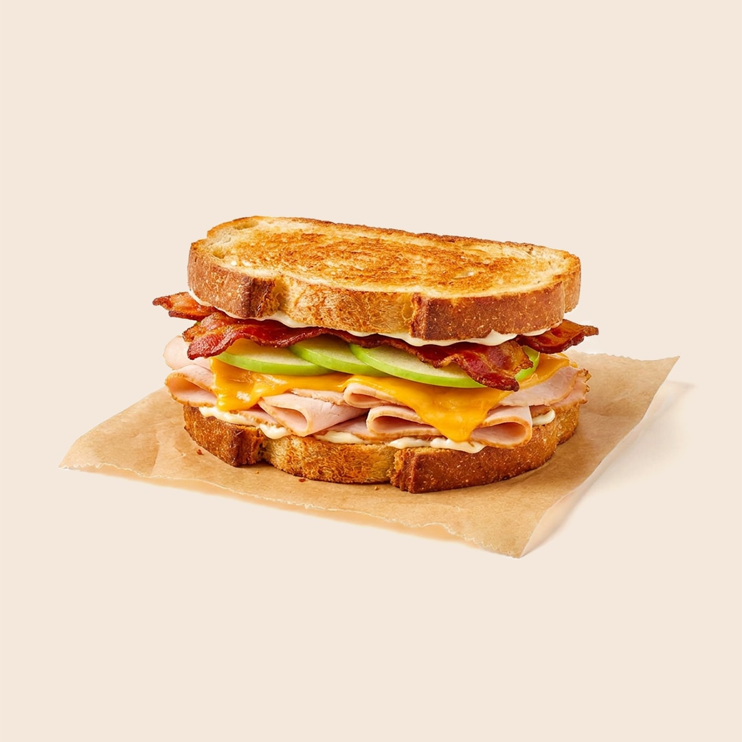 Vermonter sandwich on toasted sourdough with turkey, sharp cheddar, sliced green apples, bacon, and mayo.